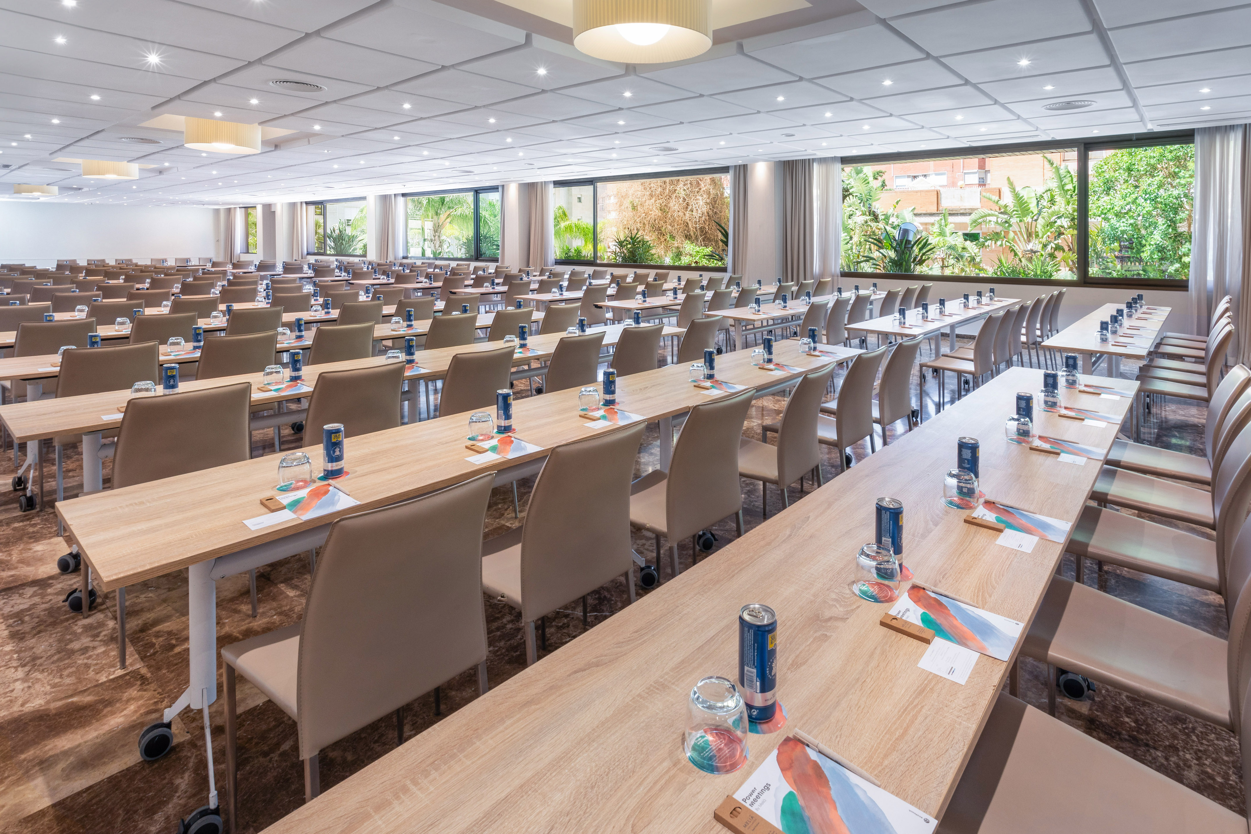 Hotel conference room with classroom style tables and chairs, large windows.