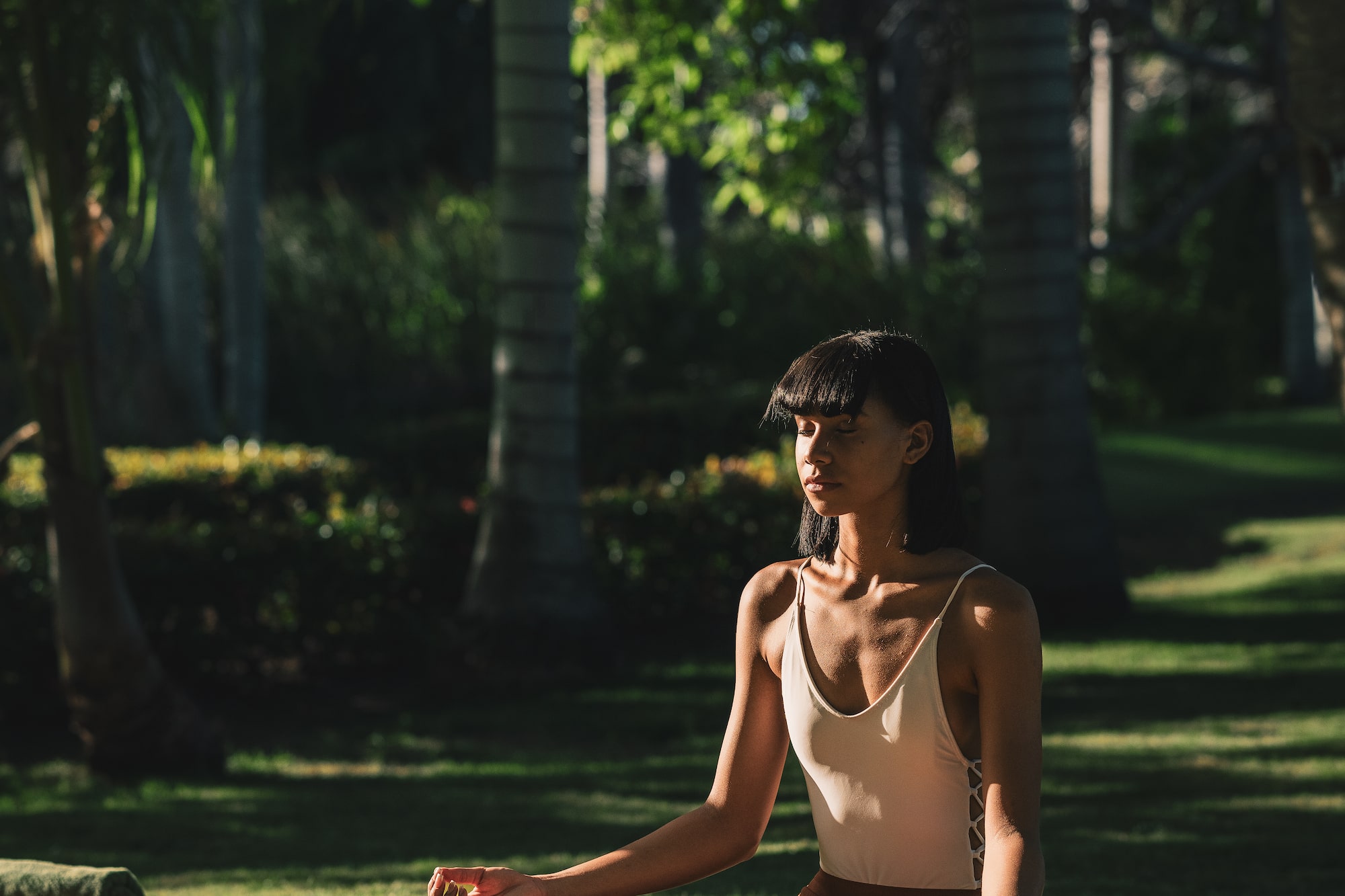 a woman sitting on a mat in the grass