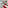 Modern hotel room with red bedding, balcony city view, white armchair, wood paneling.