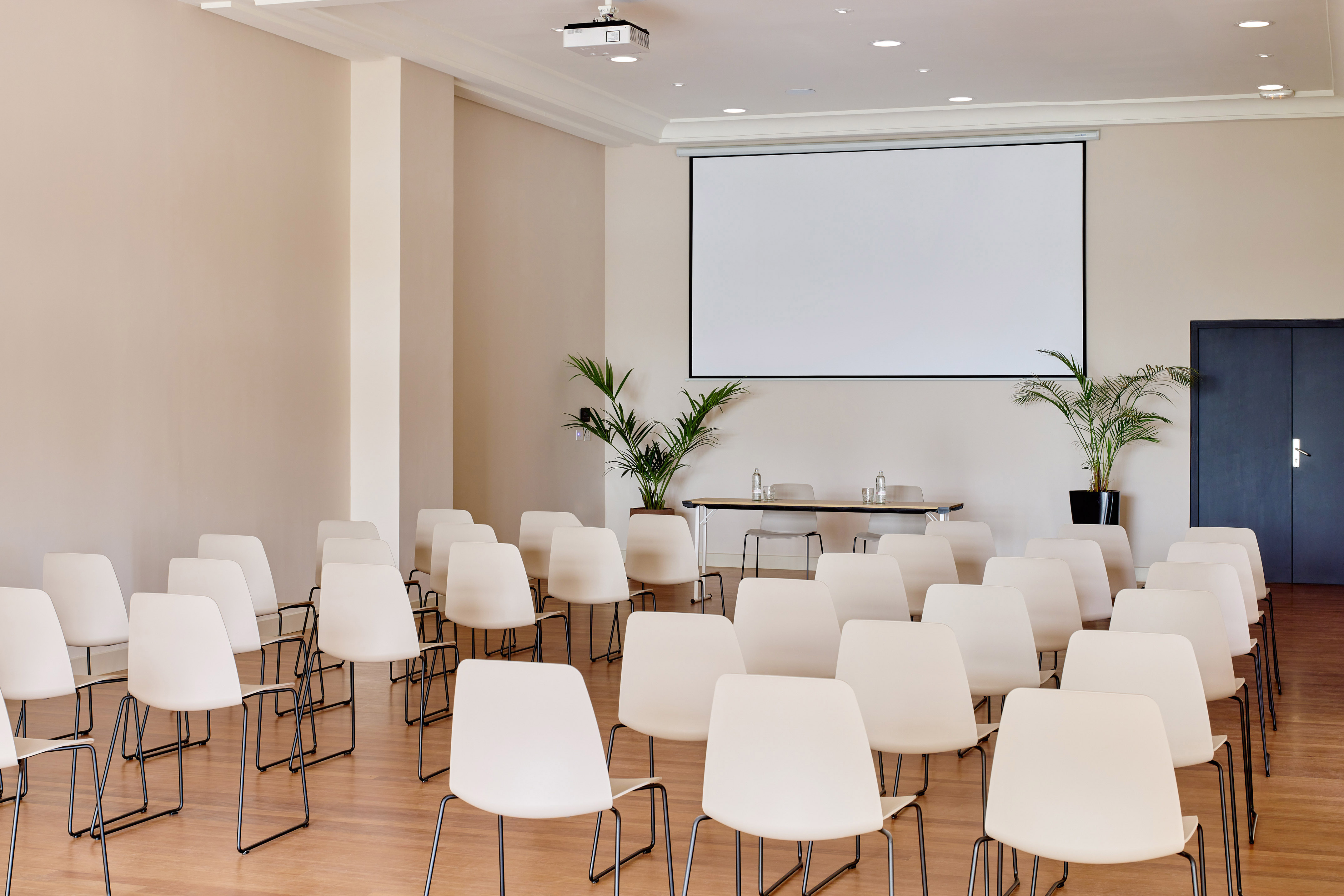 Empty modern conference room with projection screen and rows of chairs.