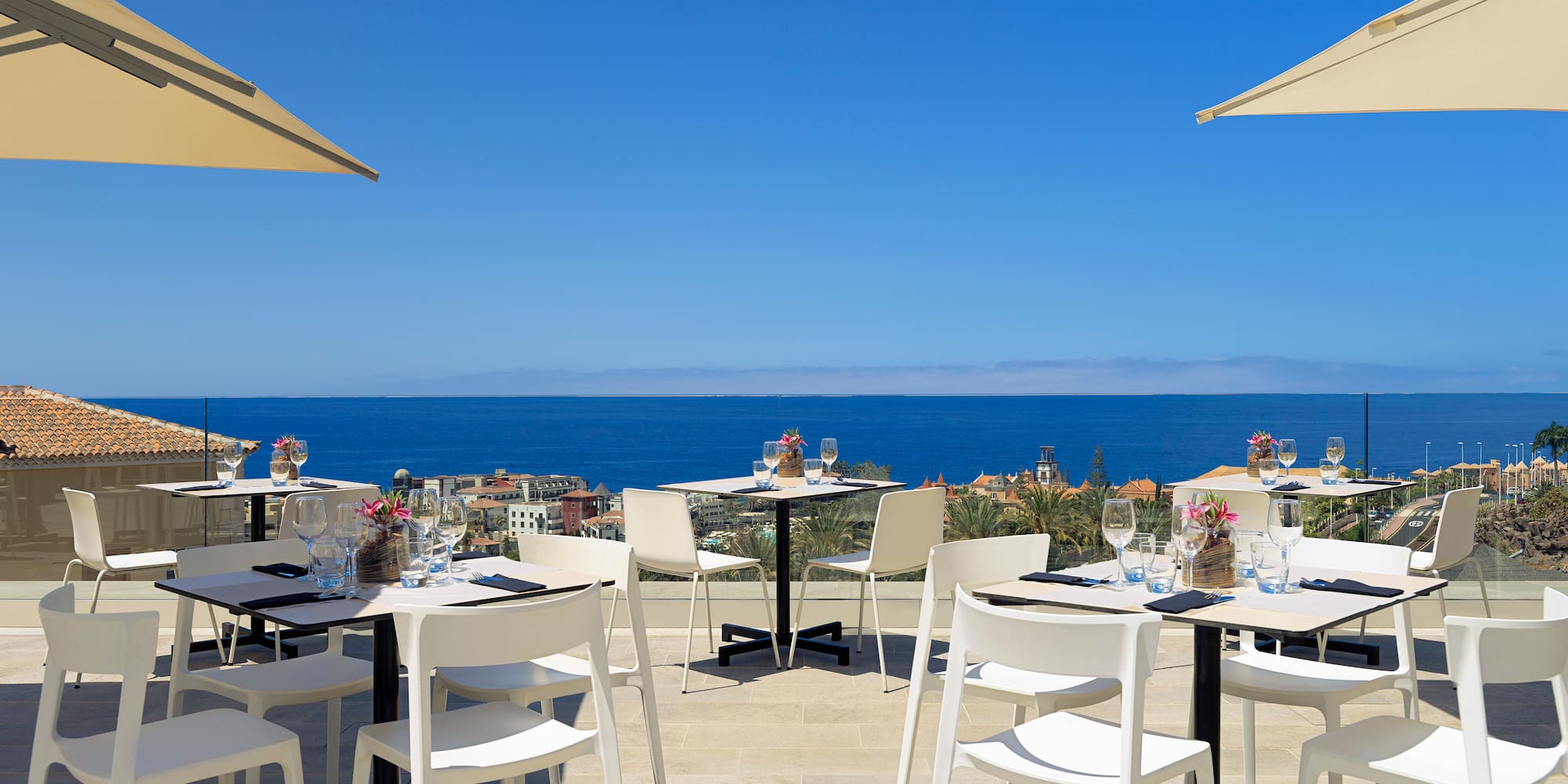 a table and chairs on a patio with a body of water in the background
