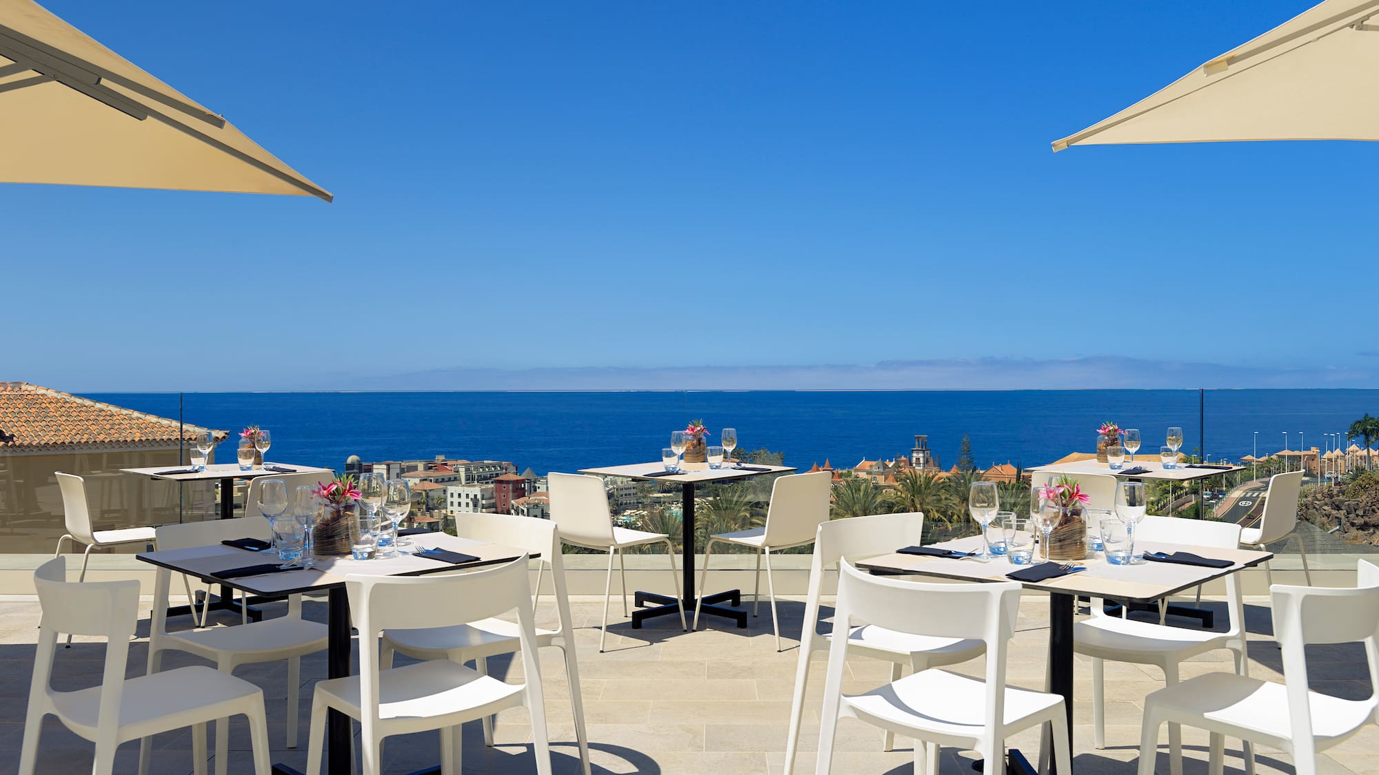 a table and chairs on a patio with a body of water in the background