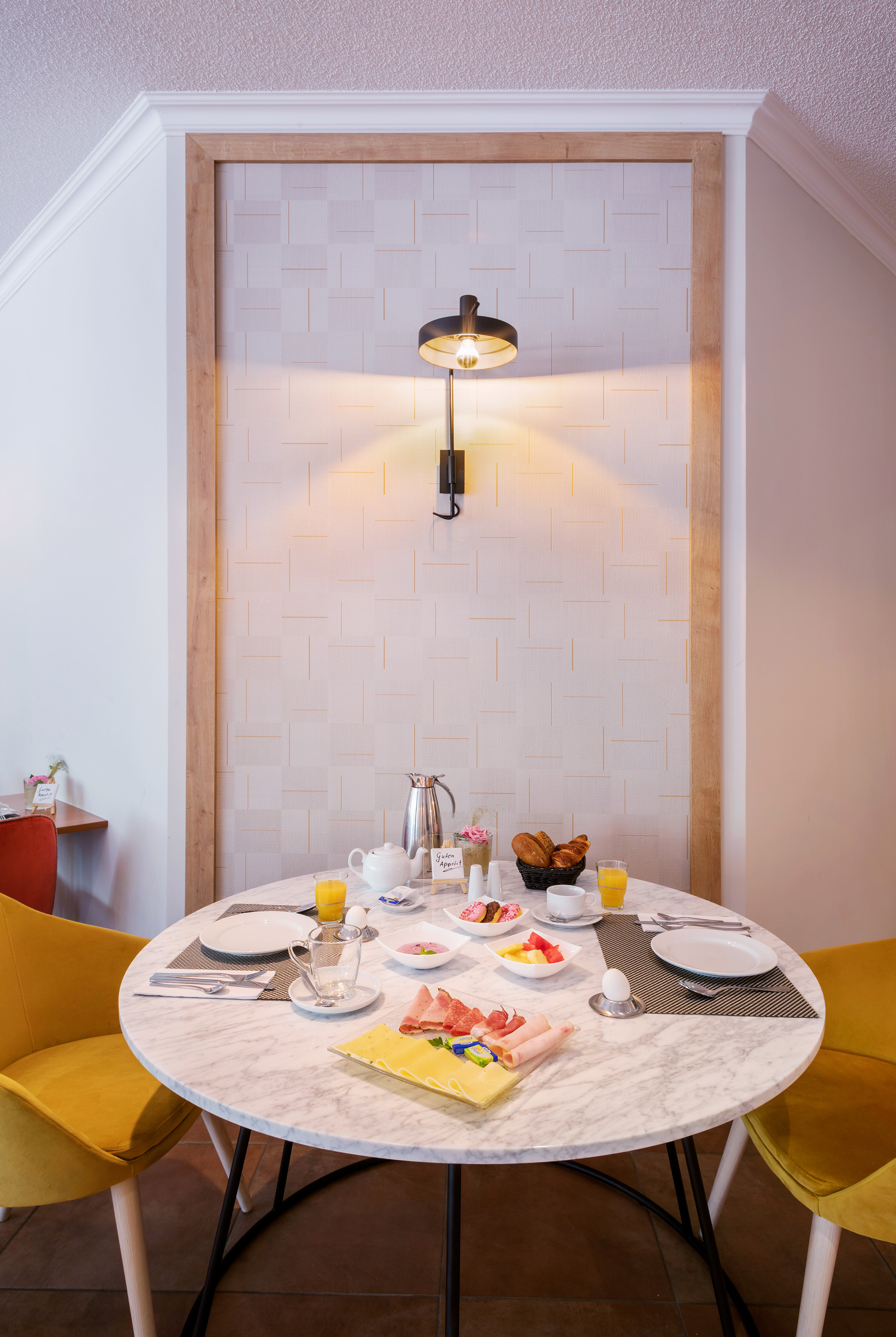 Full breakfast spread with pastries, fruit, ham, and cheese on a marble table.