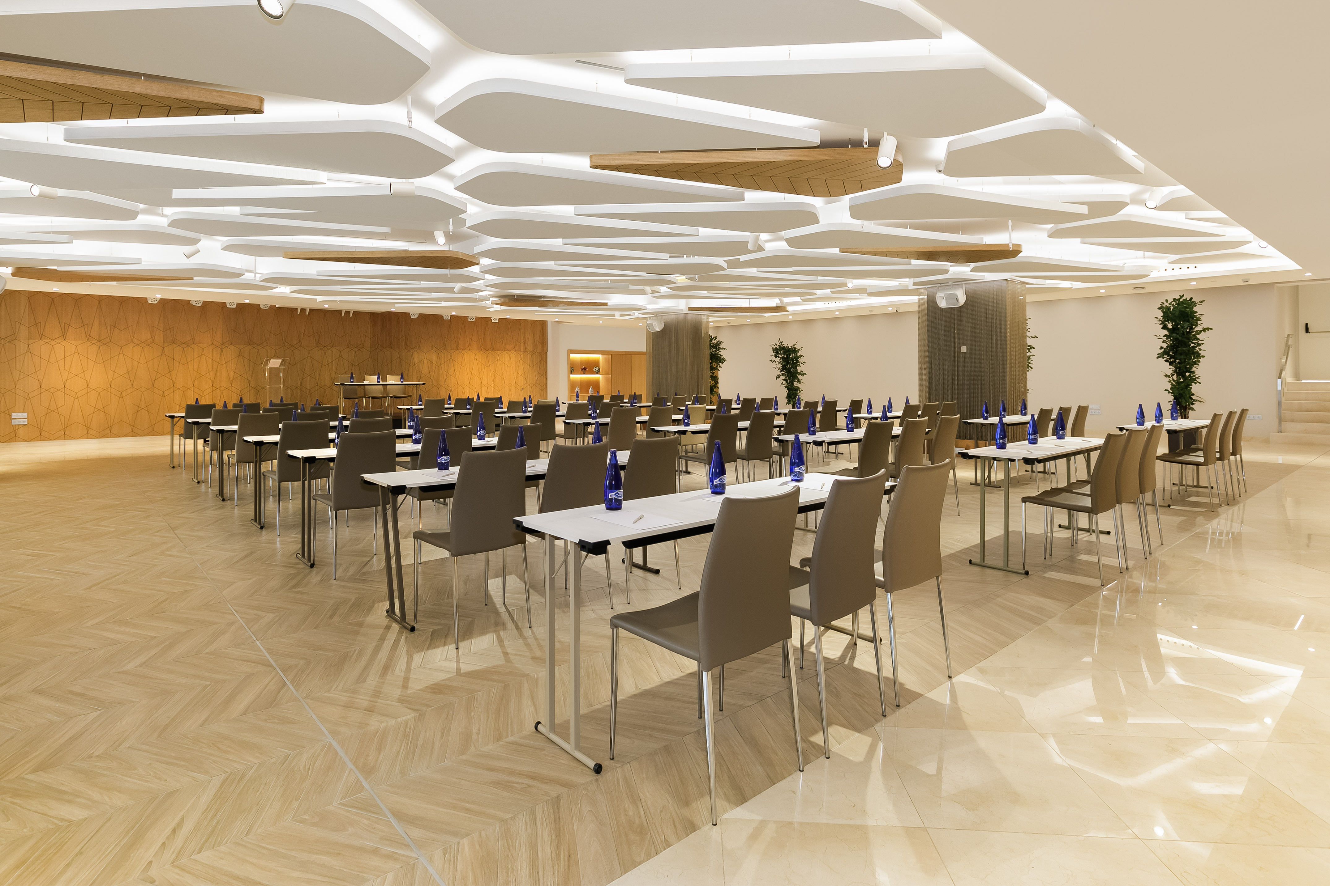 Spacious modern meeting room with tables, chairs, and unique ceiling design.