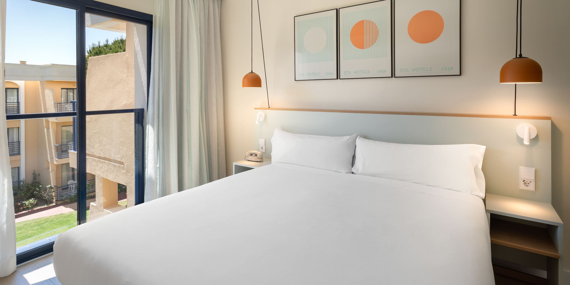Bright modern hotel room with double bed, balcony, and contemporary decor.