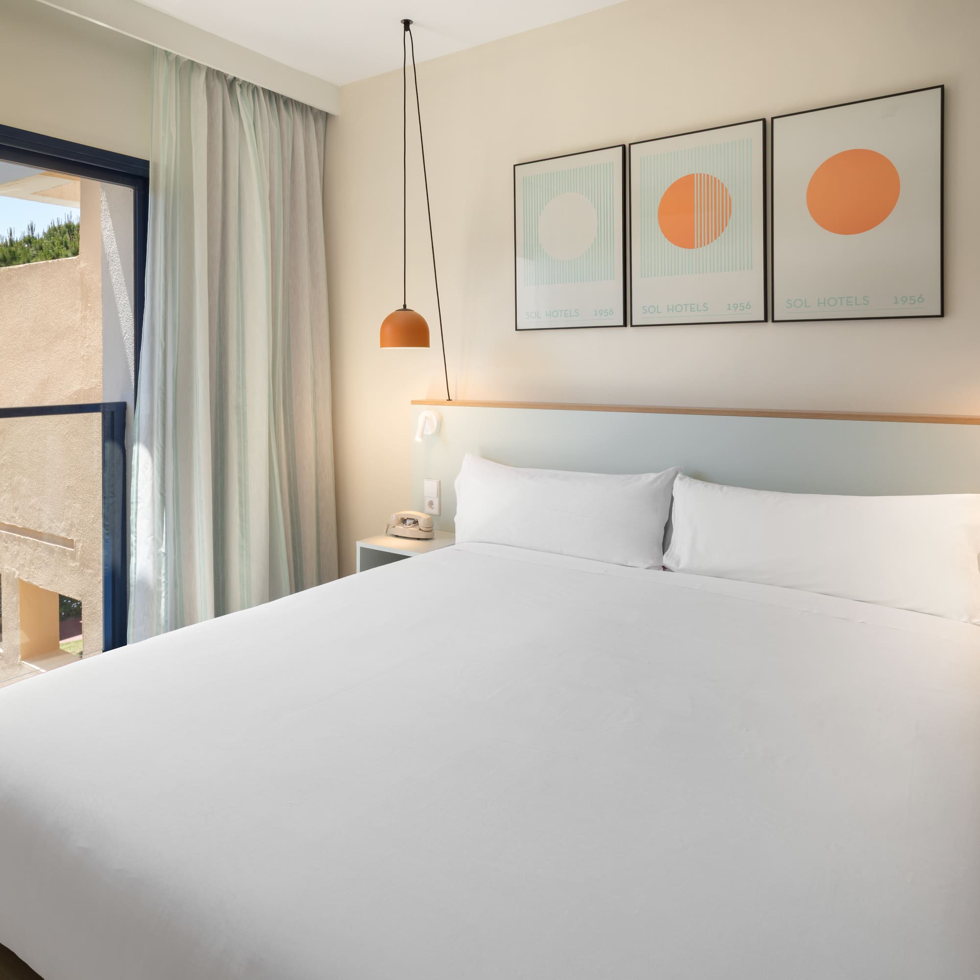 Bright modern hotel room with double bed, balcony, and contemporary decor.