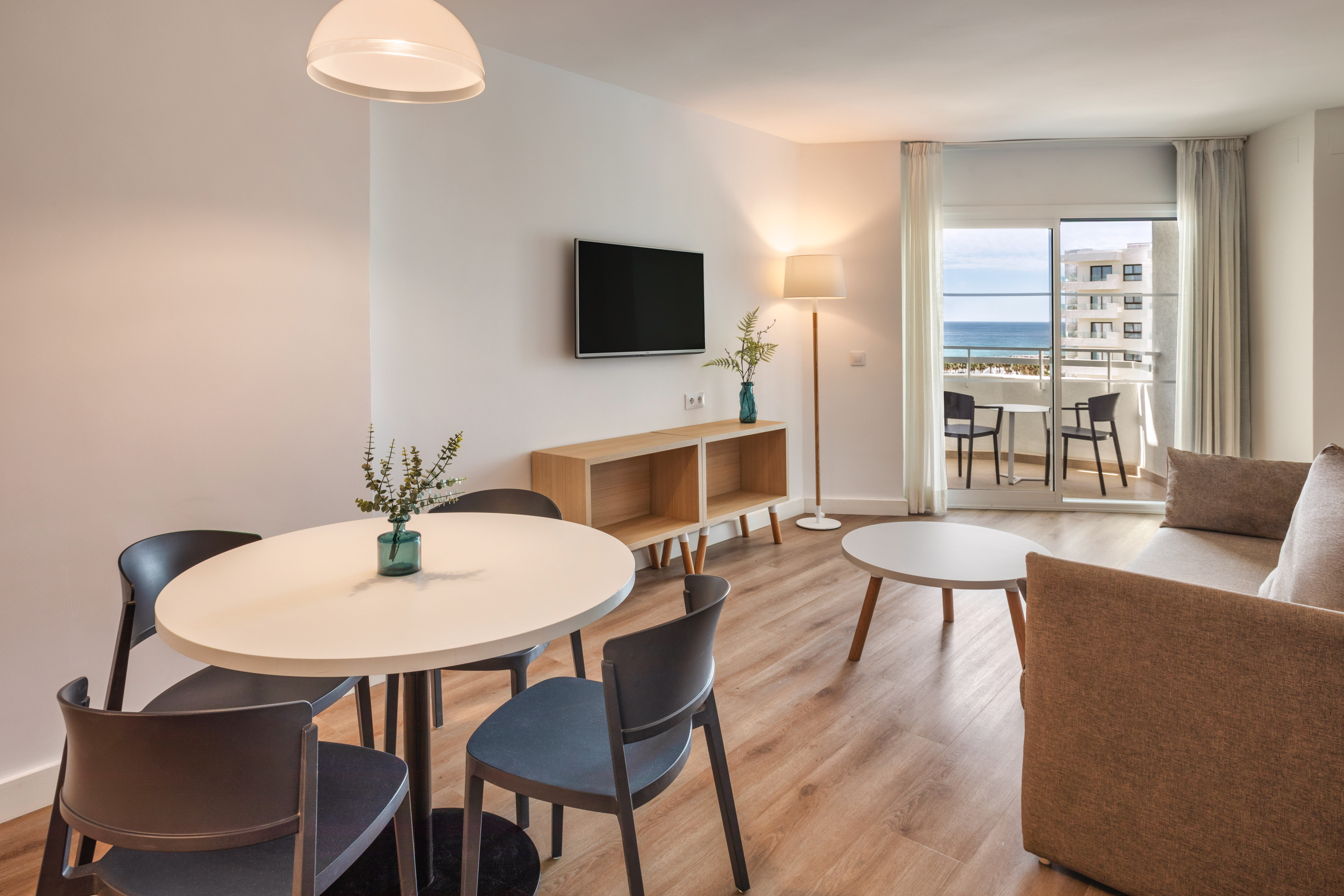Bright, modern apartment living/dining room with ocean view balcony.