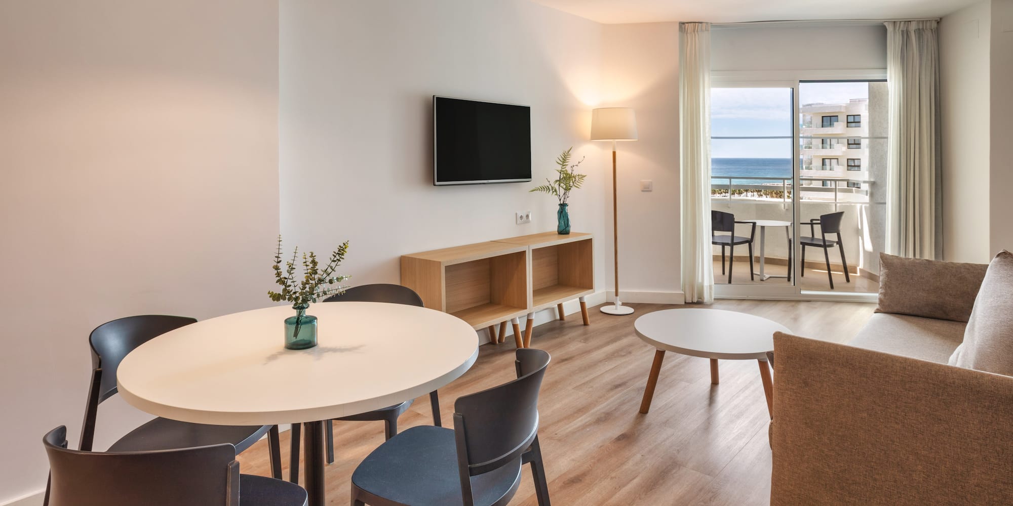 Modern apartment living room with dining area and ocean view balcony.