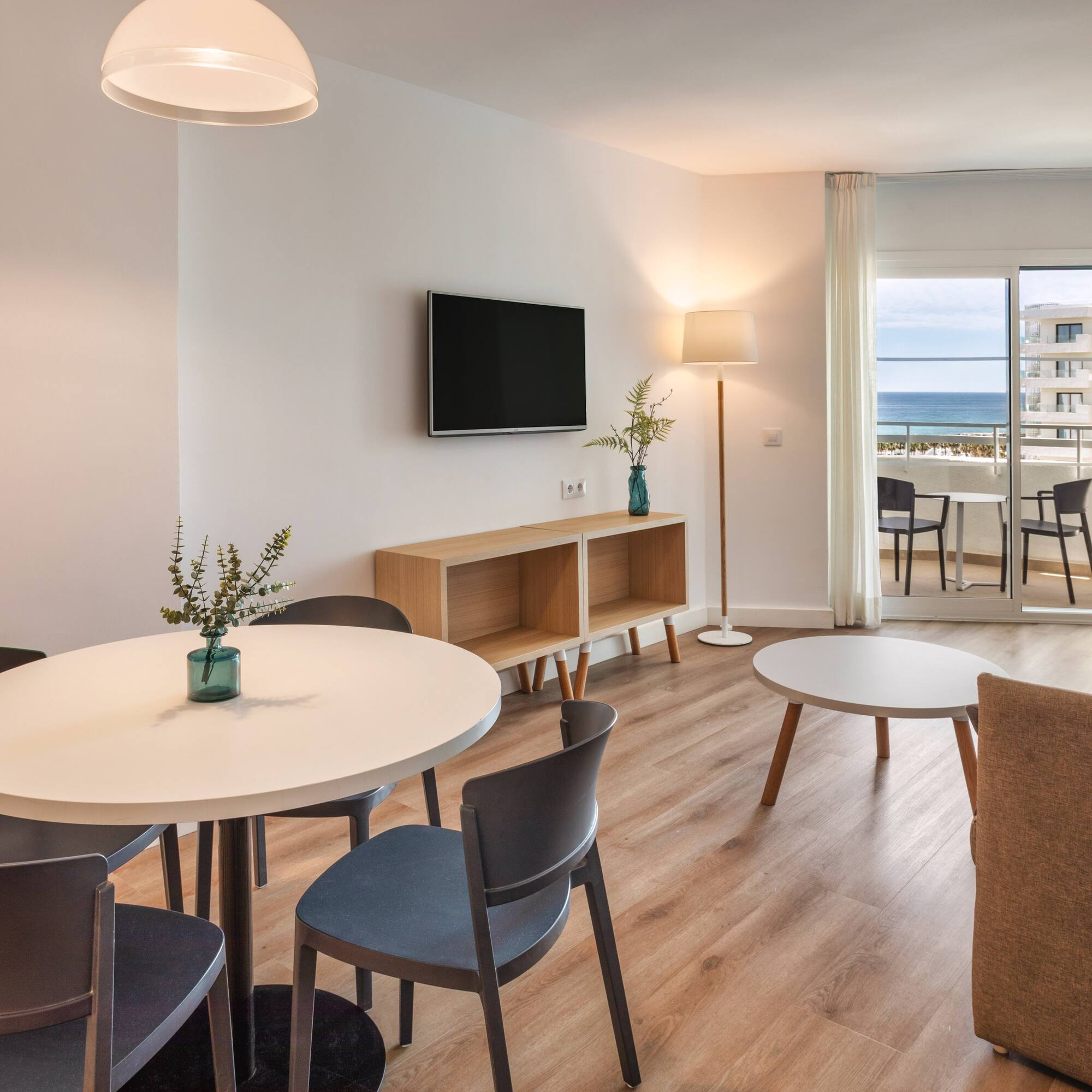 Modern apartment living room with dining area and ocean view balcony.