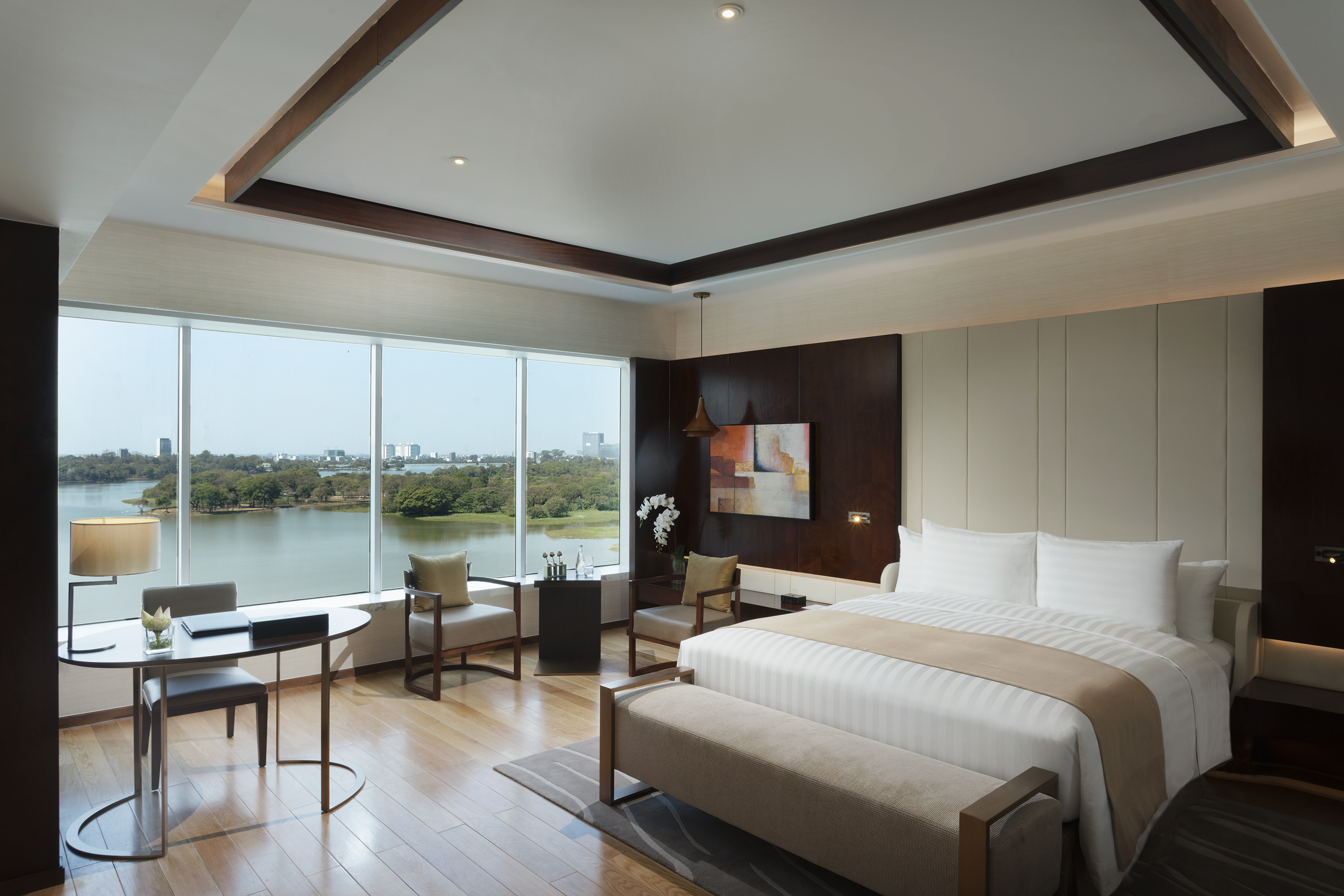 Modern hotel room with stunning lake view, king bed, and stylish workspace.