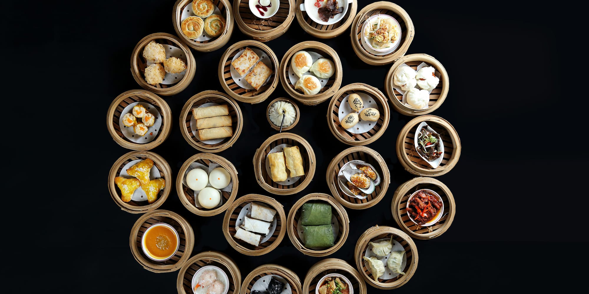 Circular arrangement of diverse dim sum dishes in bamboo steamers. Chinese food.