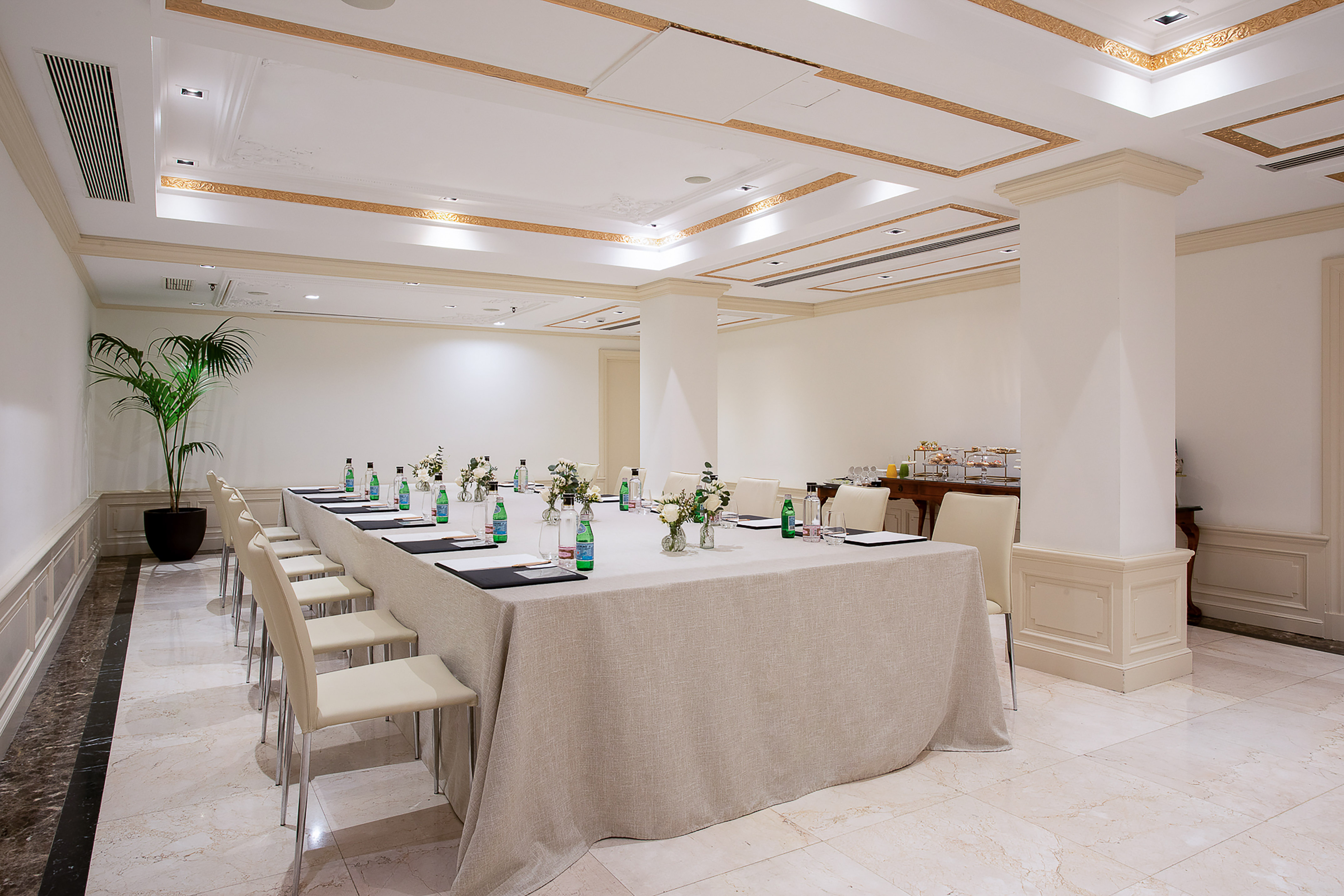 Professional conference room setup with long table, chairs, and refreshments.
