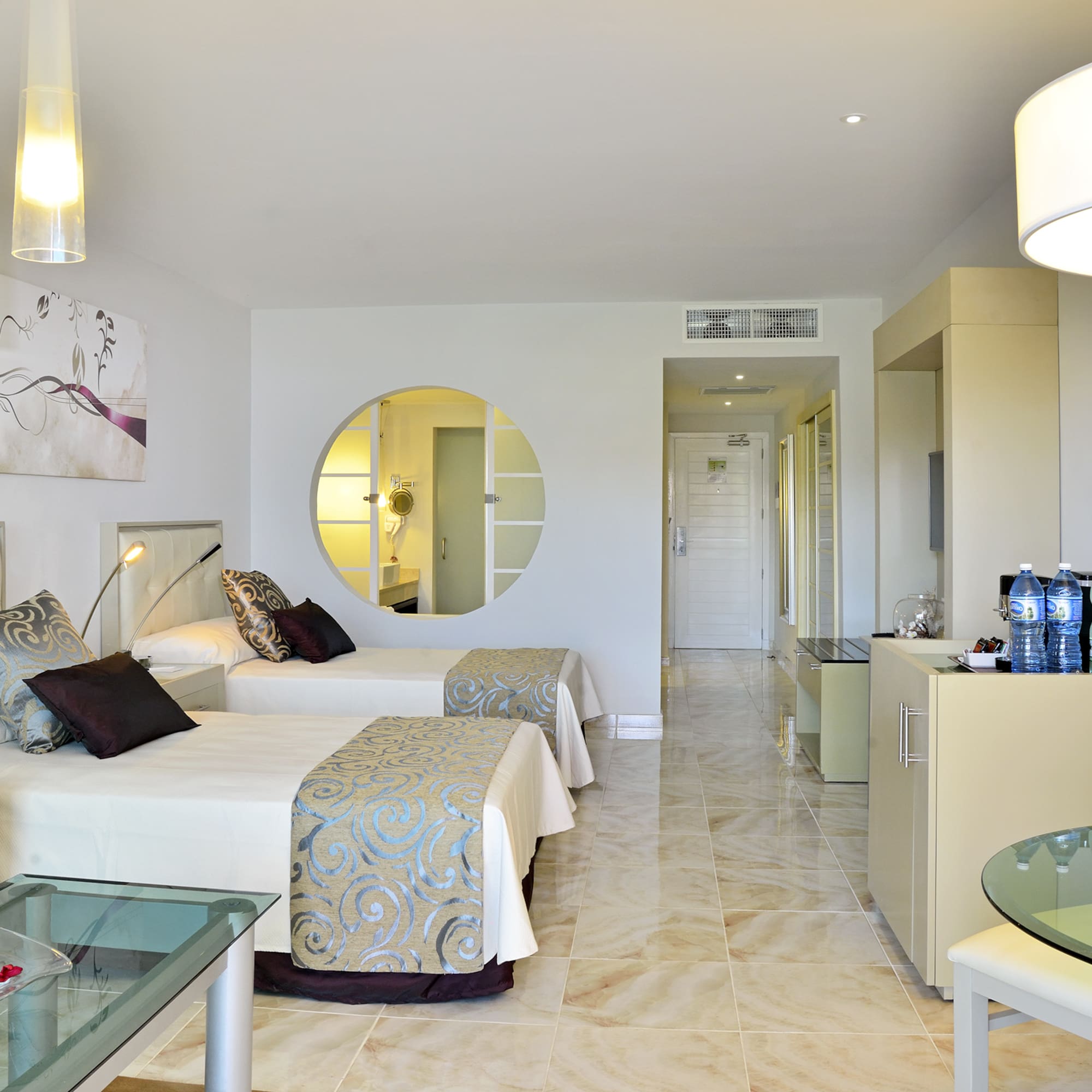 a room with two beds and a round mirror