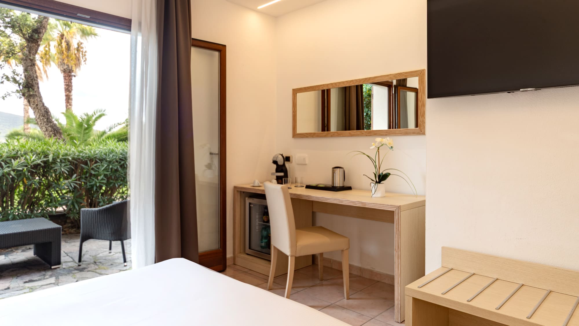 Hotel room with double bed, desk, TV, and private garden terrace.