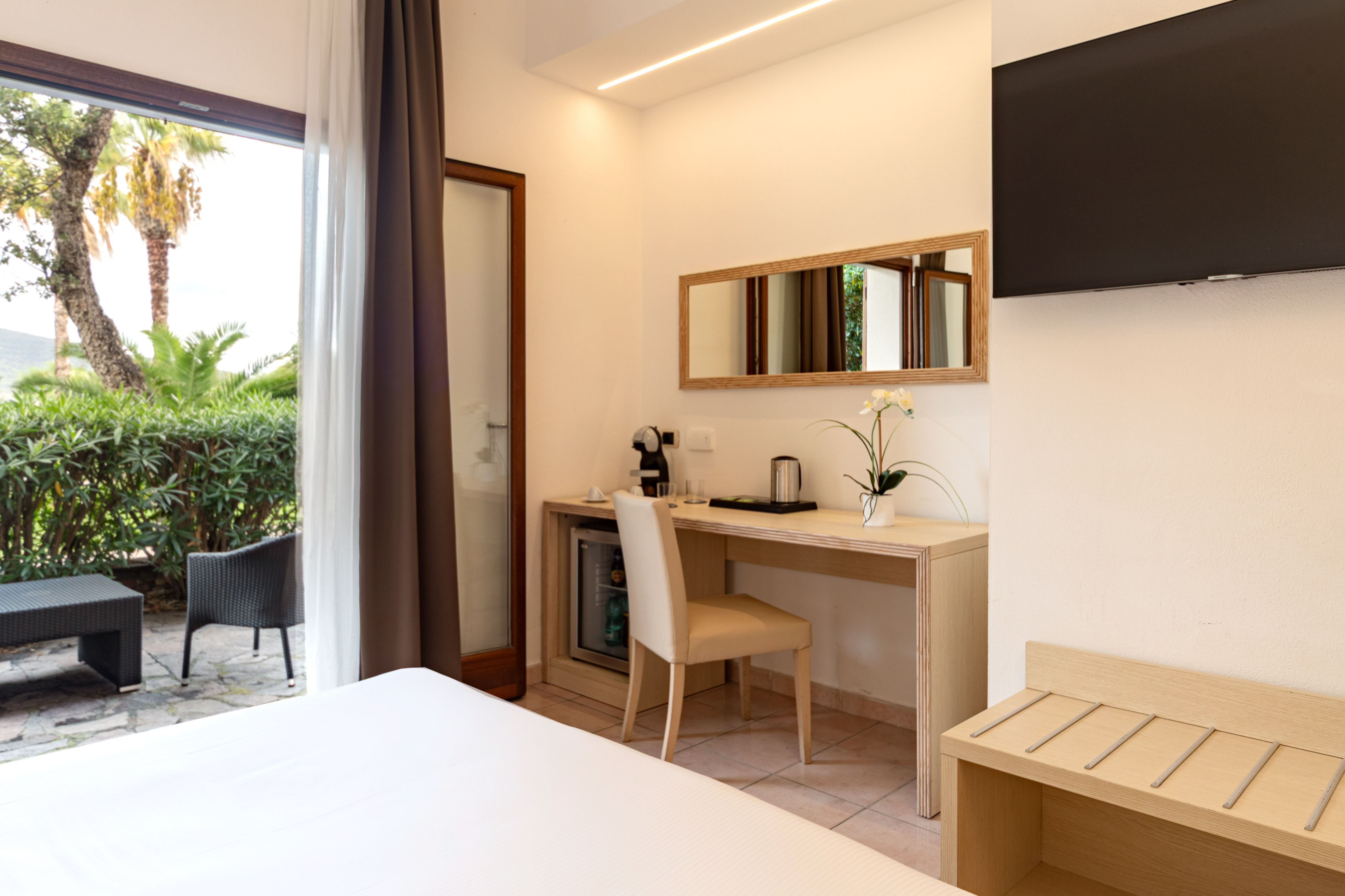 Hotel room with double bed, desk, TV, and private garden terrace.