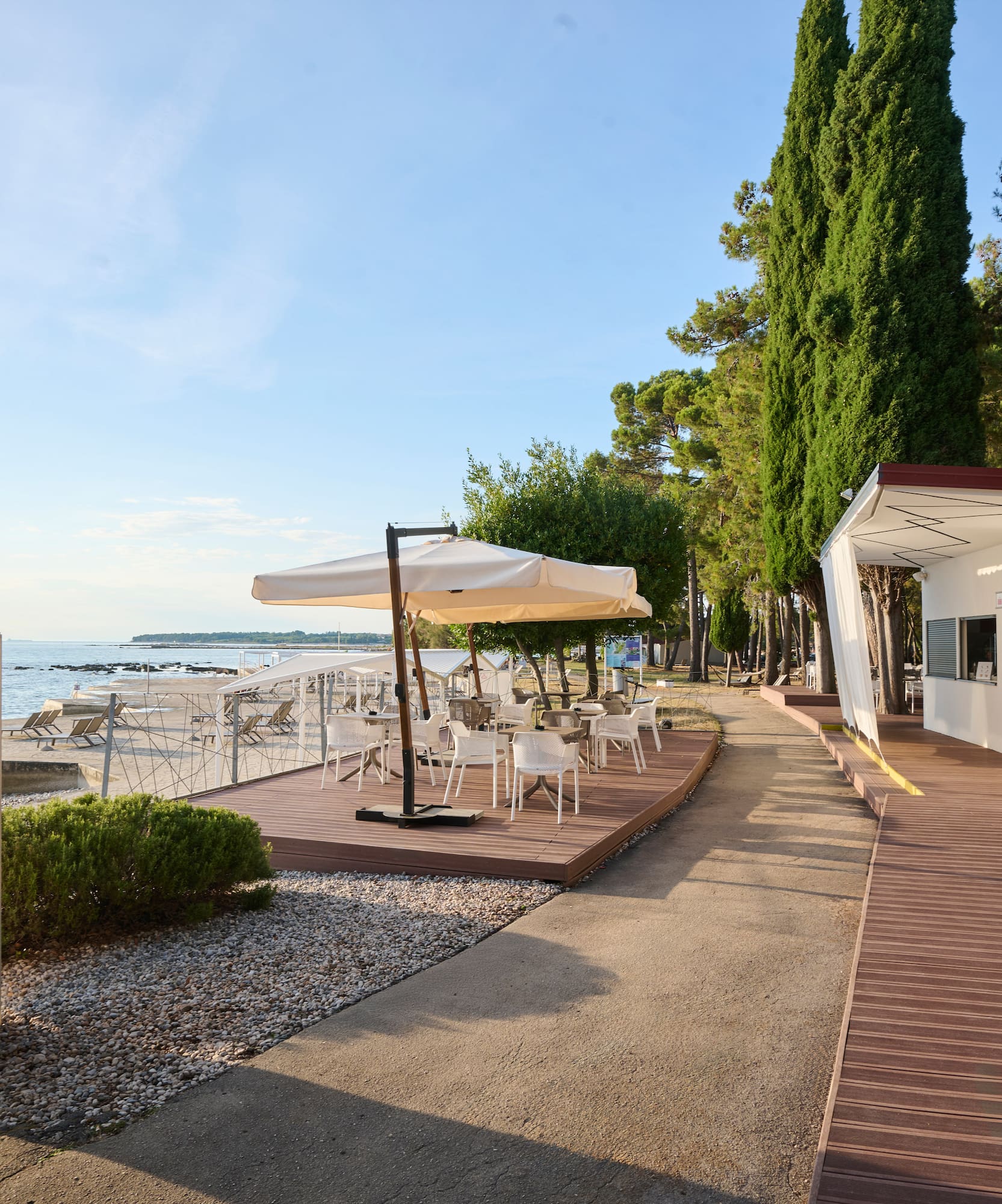 a white building with white chairs and umbrellas on a beach