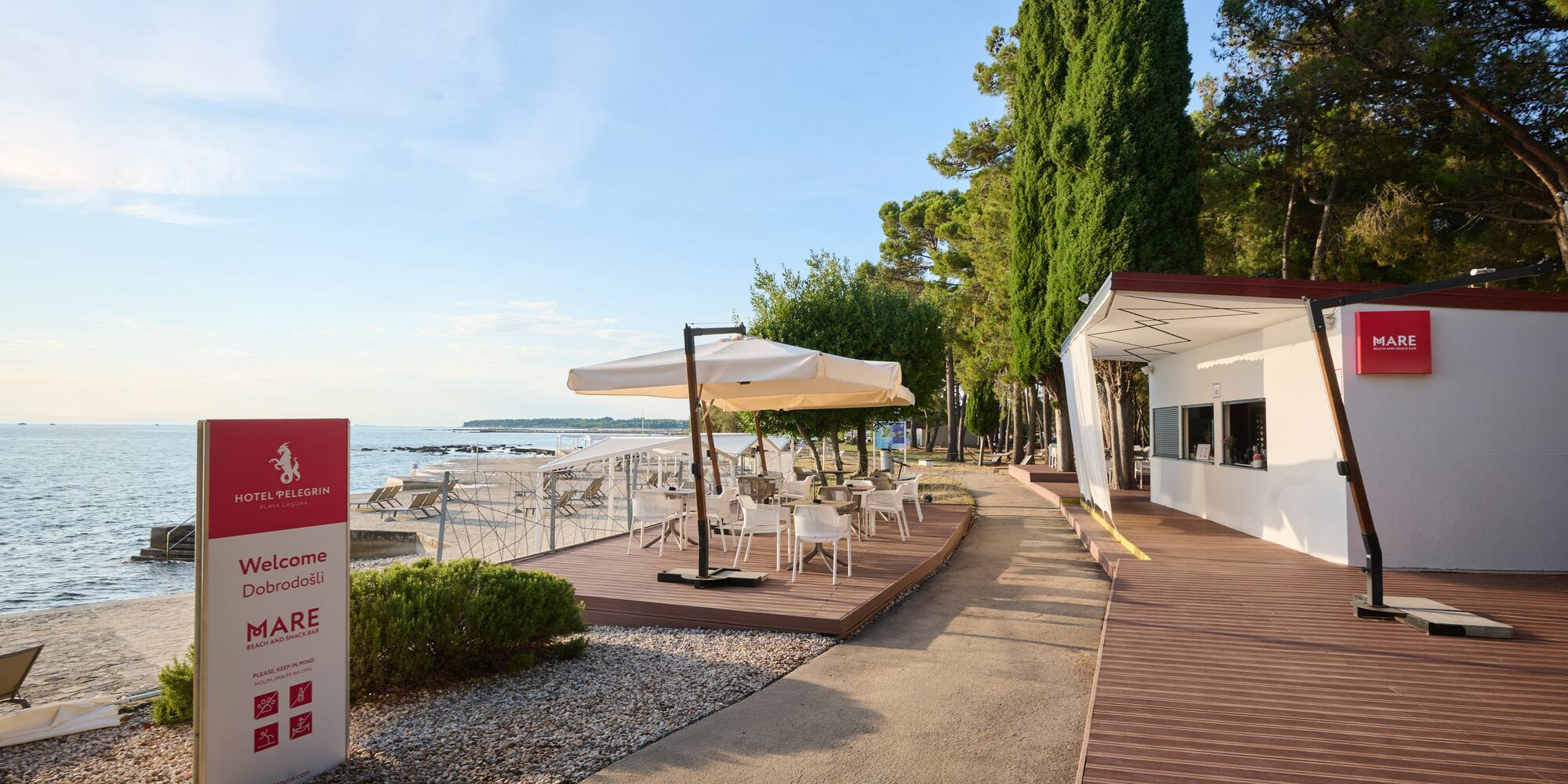 a white building with white chairs and umbrellas on a beach