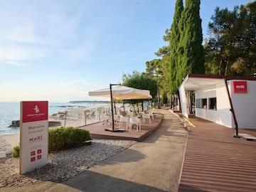 a white building with white chairs and umbrellas on a beach