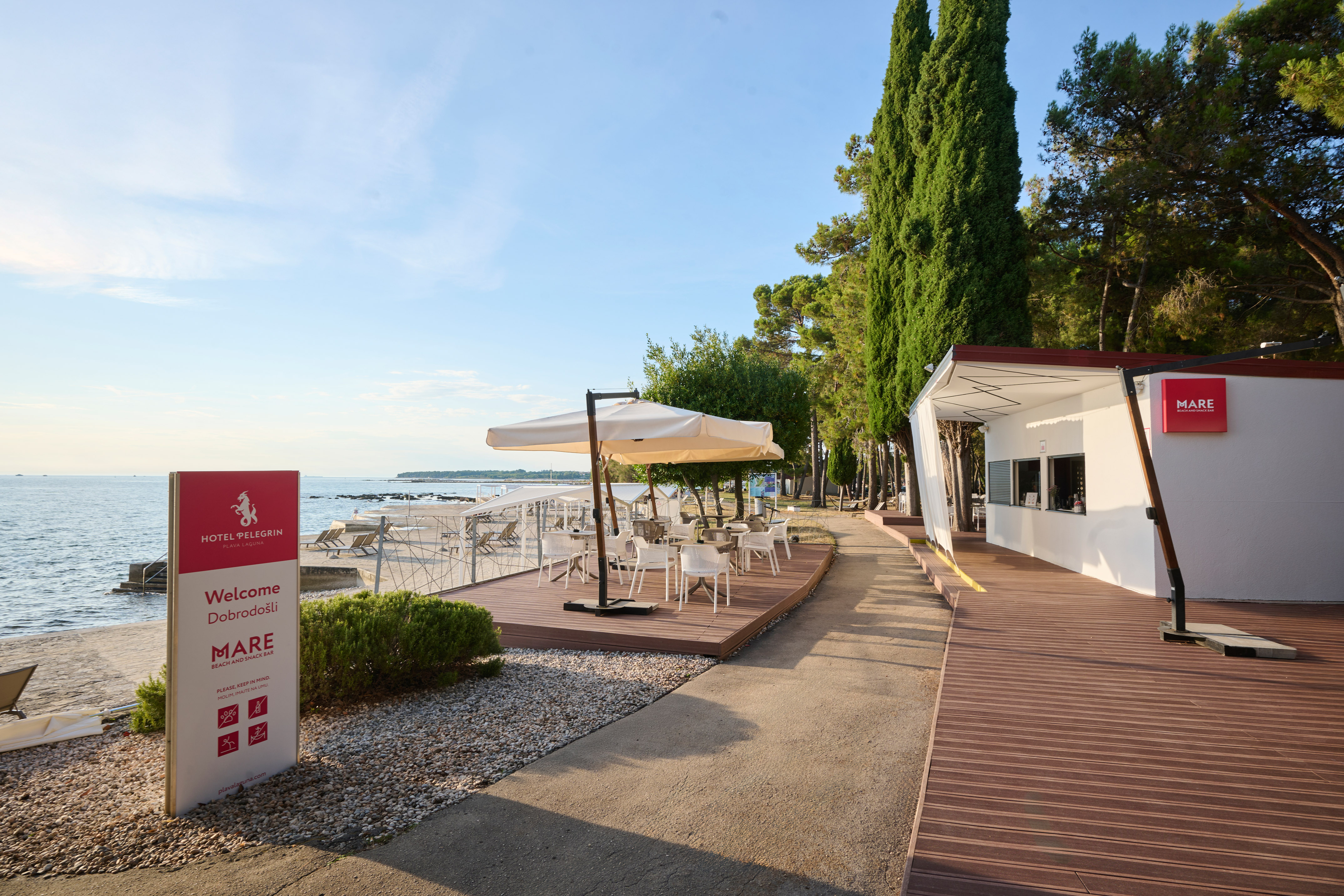 a white building with white chairs and umbrellas on a beach