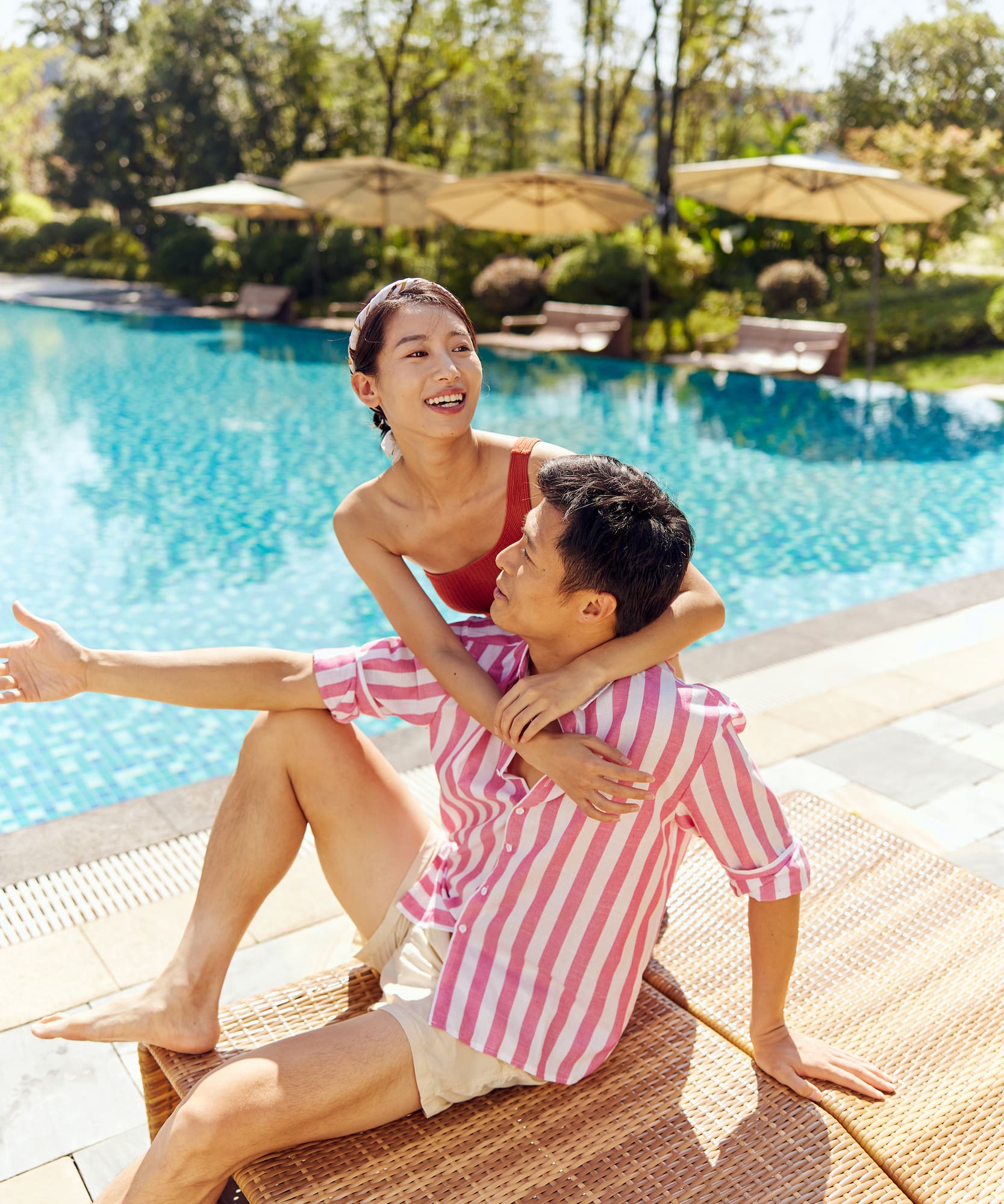a man and woman sitting by a pool