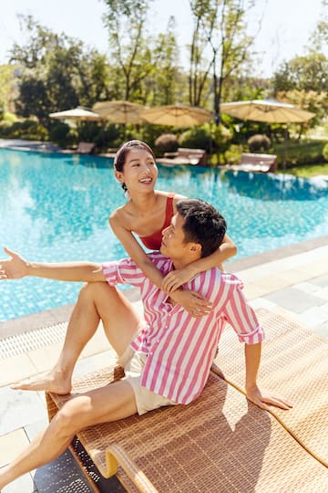 a man and woman sitting by a pool