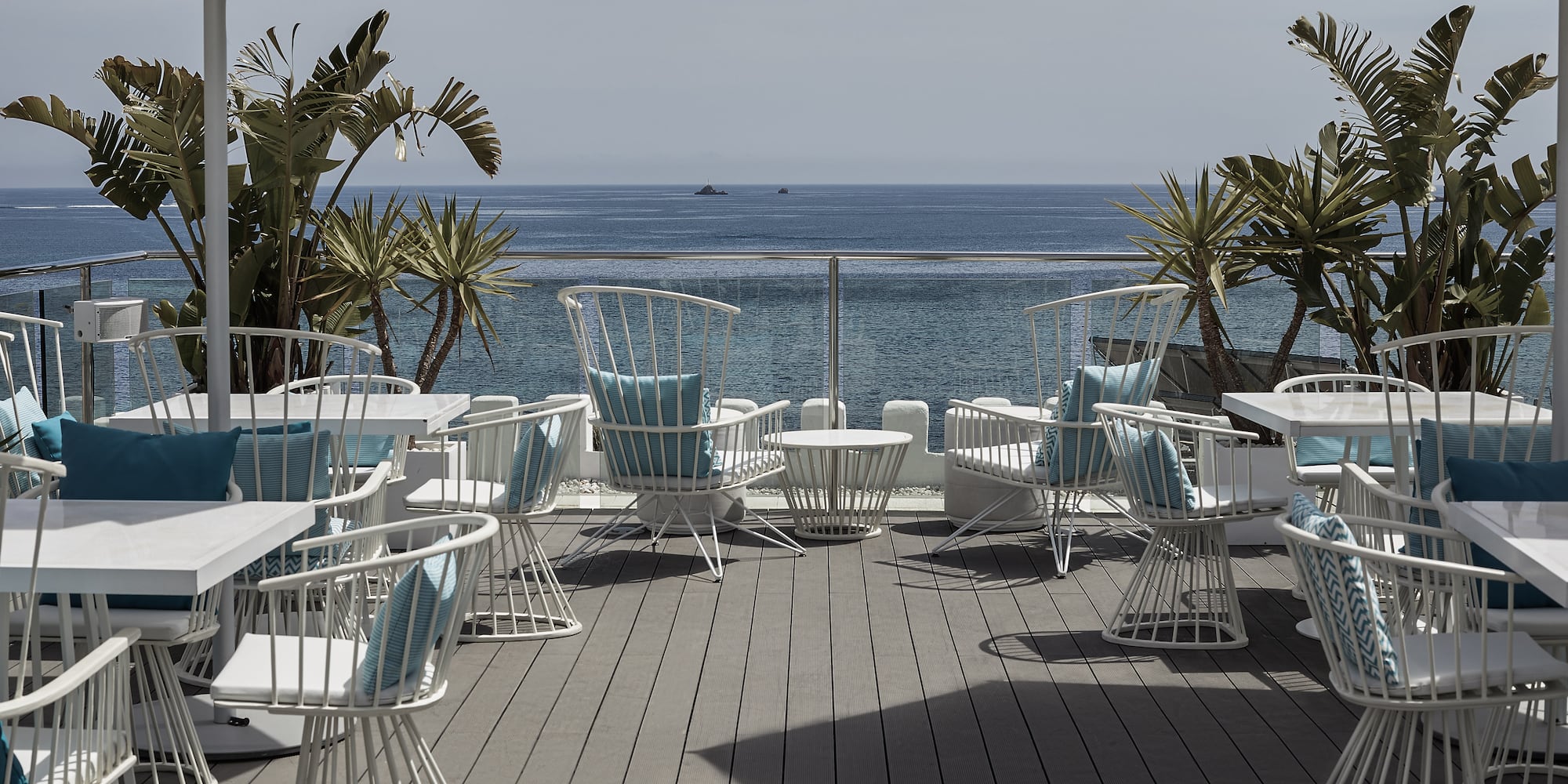a patio with chairs and tables and a view of the ocean