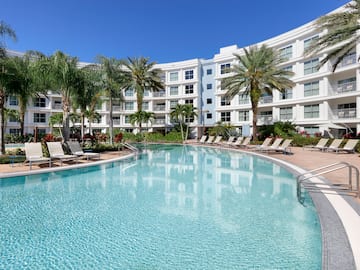 a pool with palm trees and a building