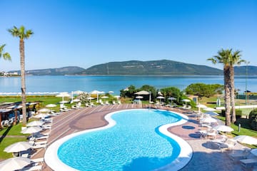 a pool with chairs and umbrellas by a body of water