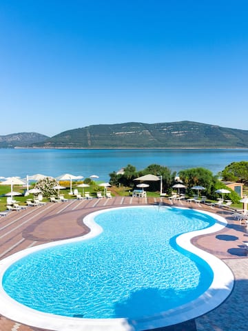 a pool with chairs and umbrellas by a body of water