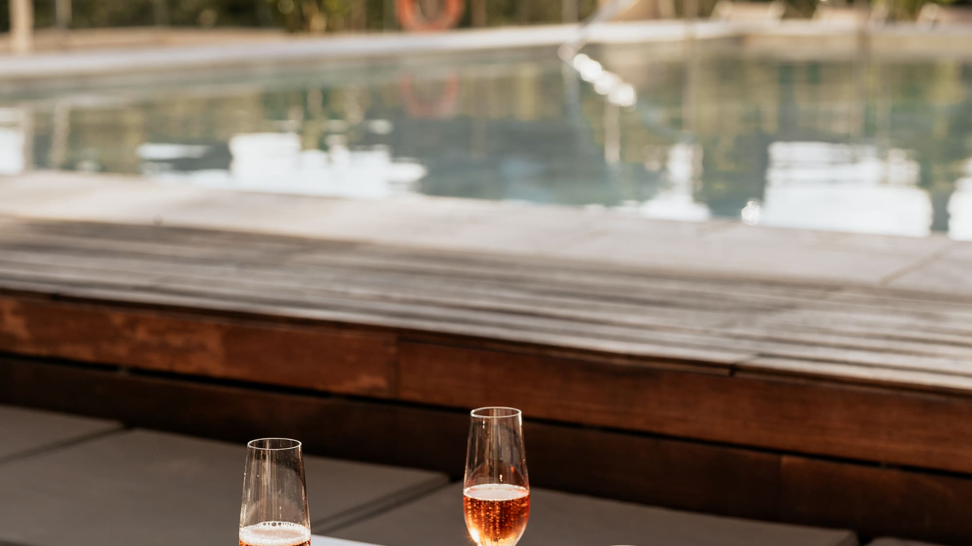 a table with wine glasses and plates on it by a pool