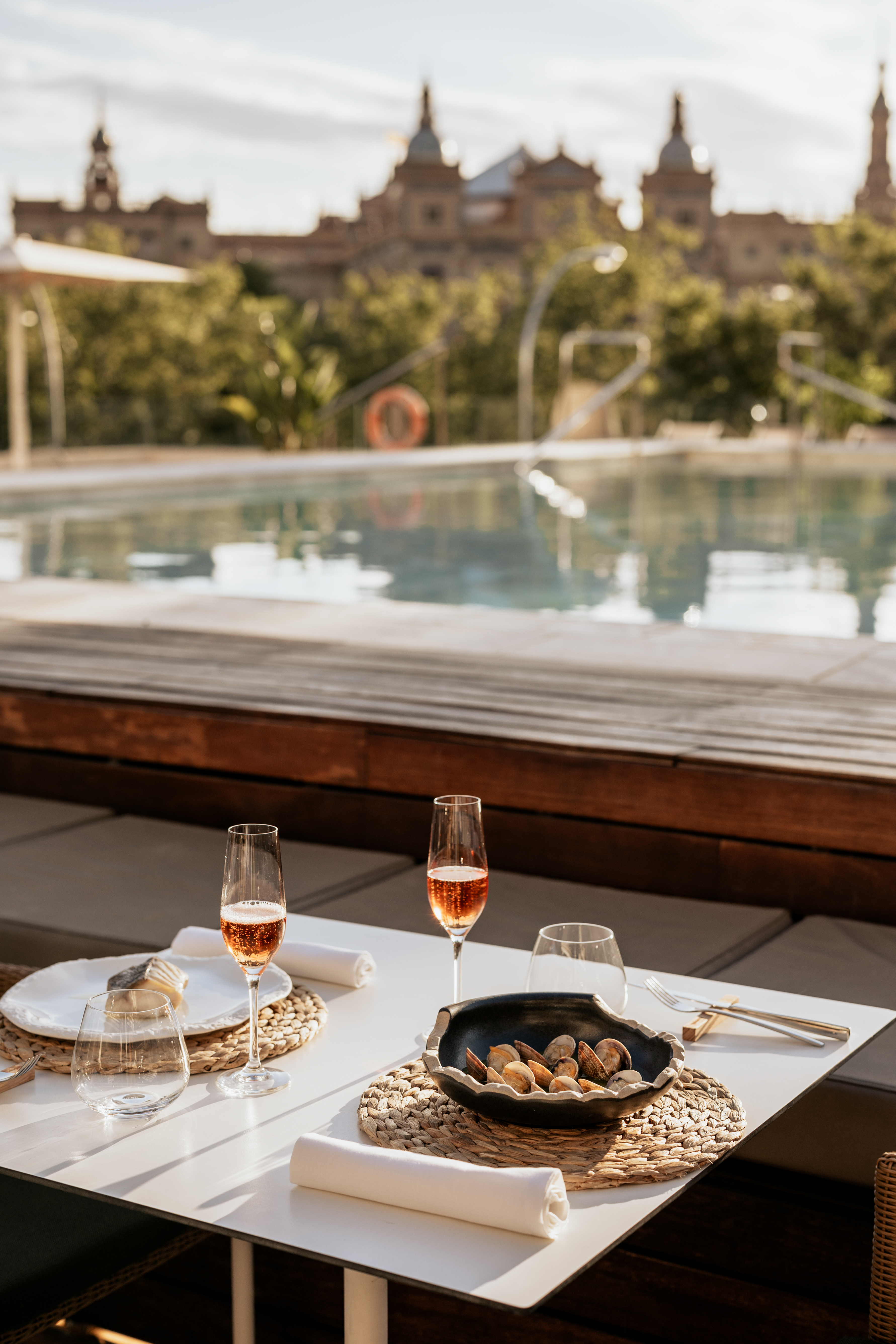 a table with wine glasses and plates on it by a pool