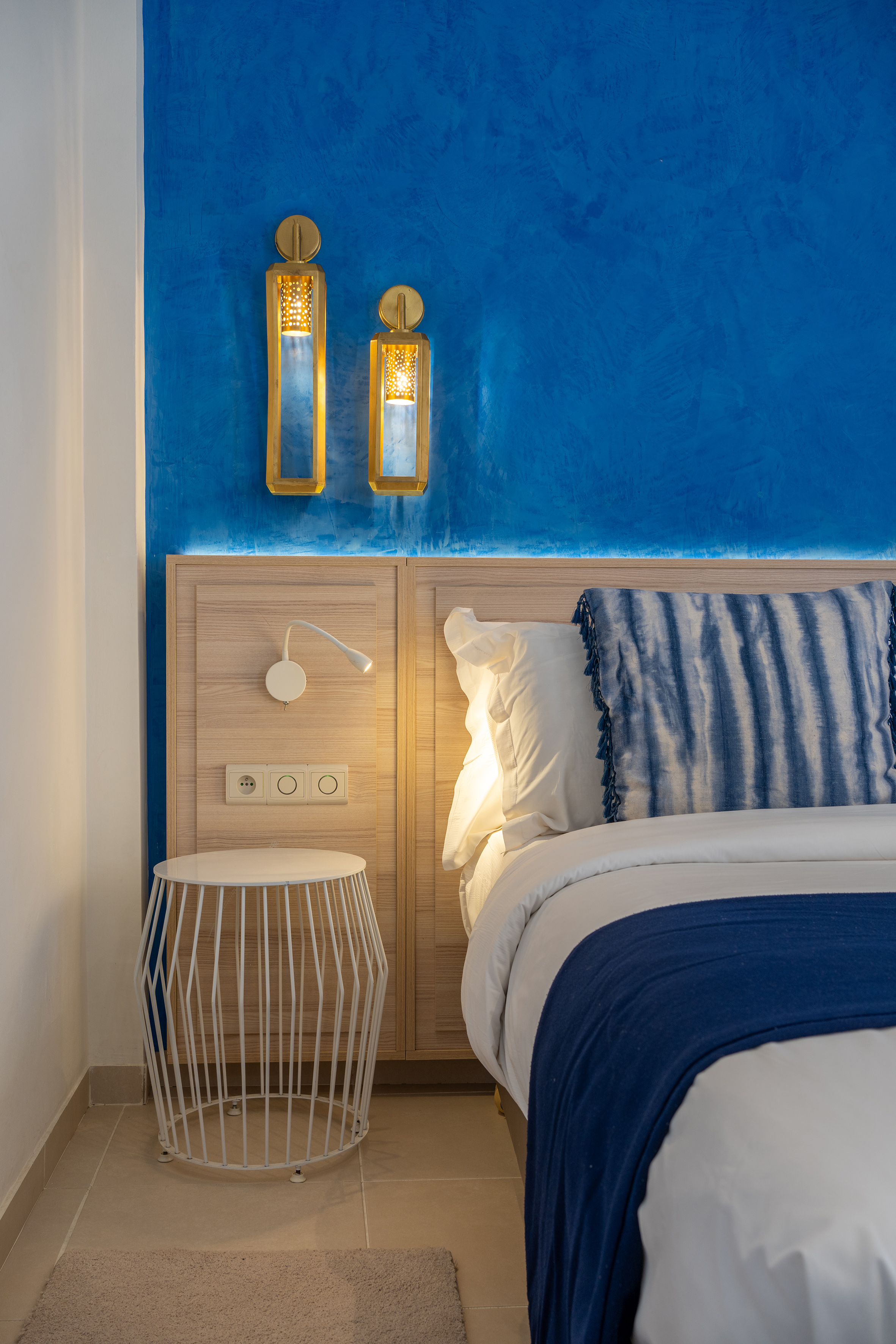 a bed with a blue and white blanket and a table