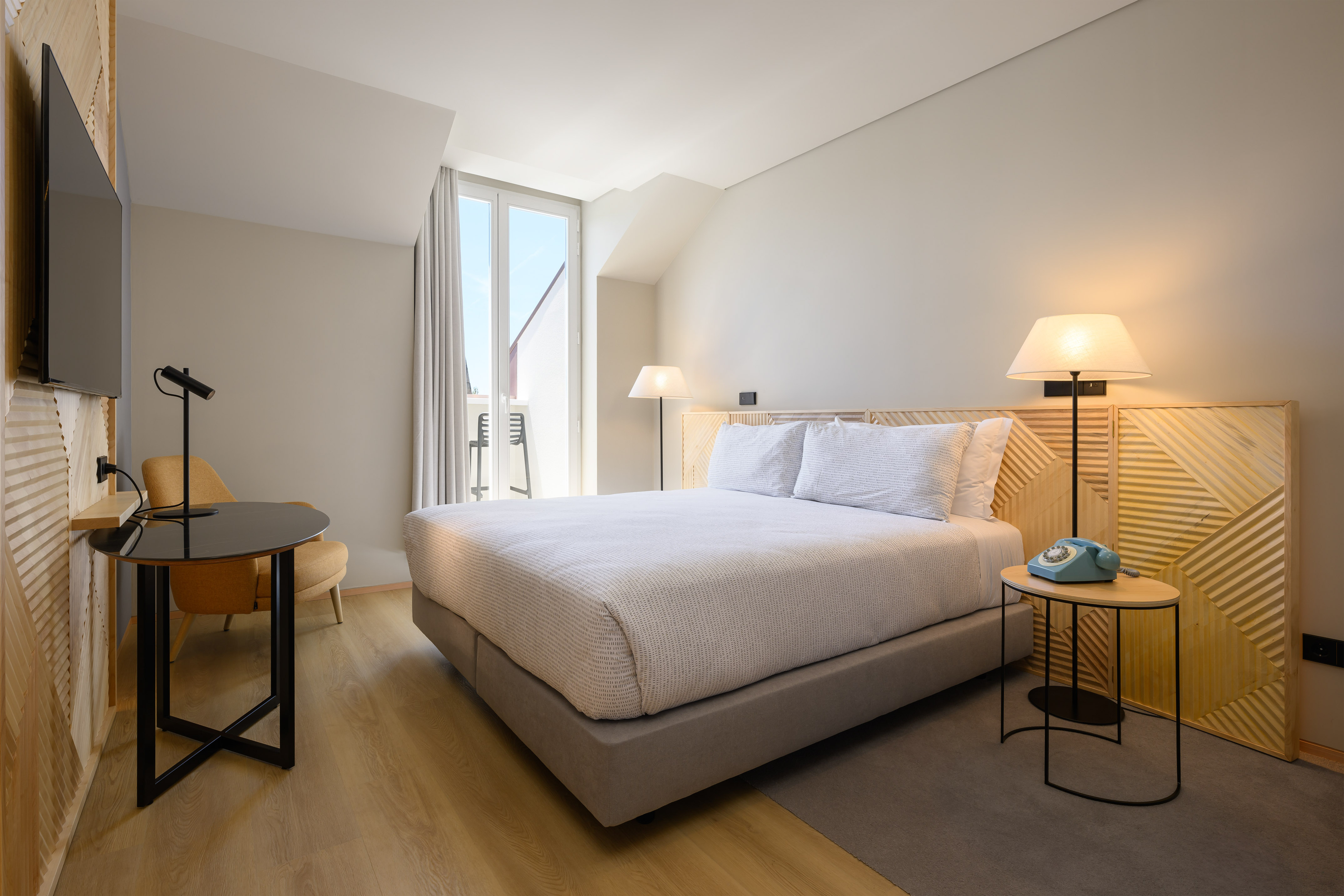 Cozy modern hotel room with queen bed, balcony, and contemporary design.