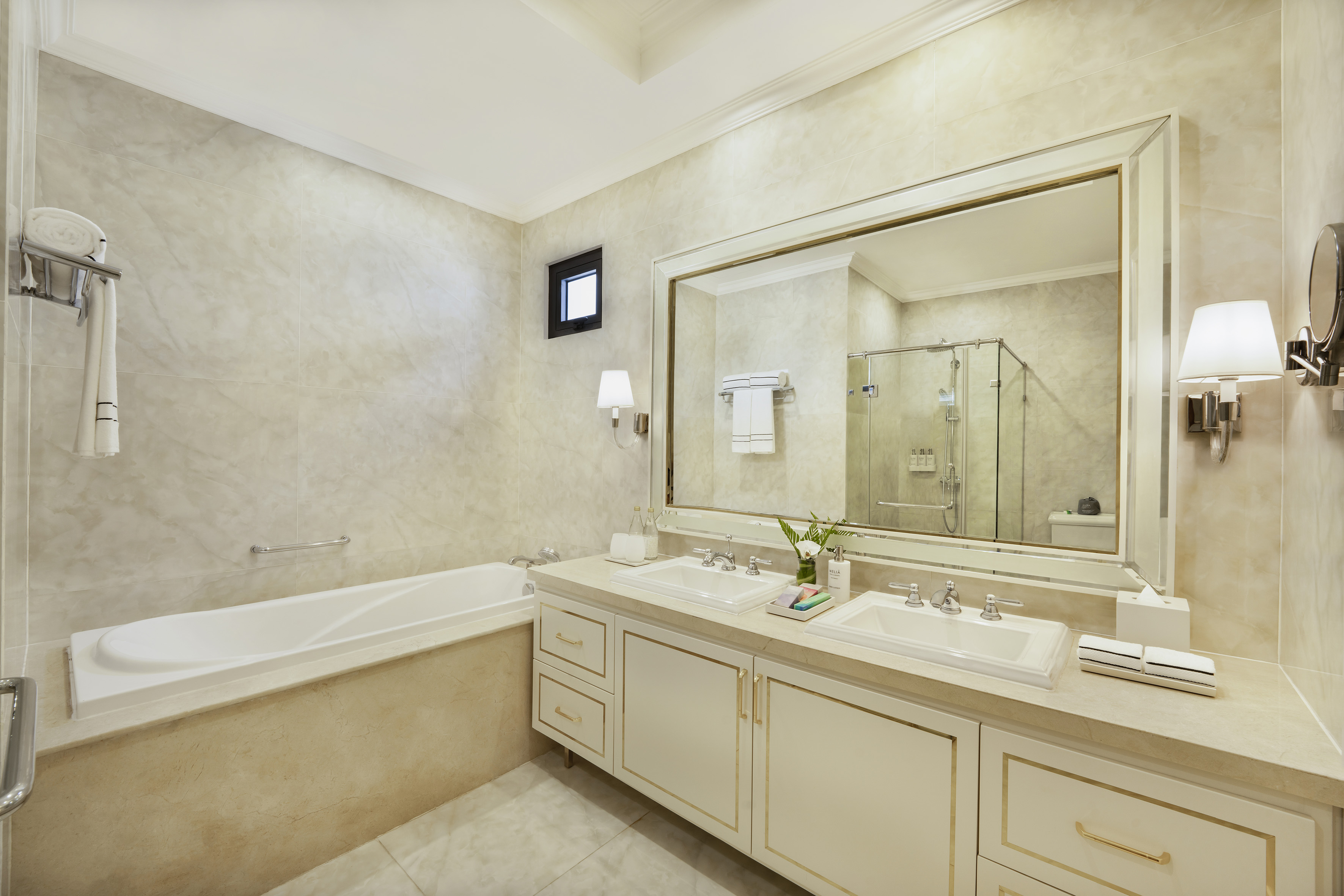 Luxury modern bathroom with double vanity, bathtub, large mirror, and separate shower.