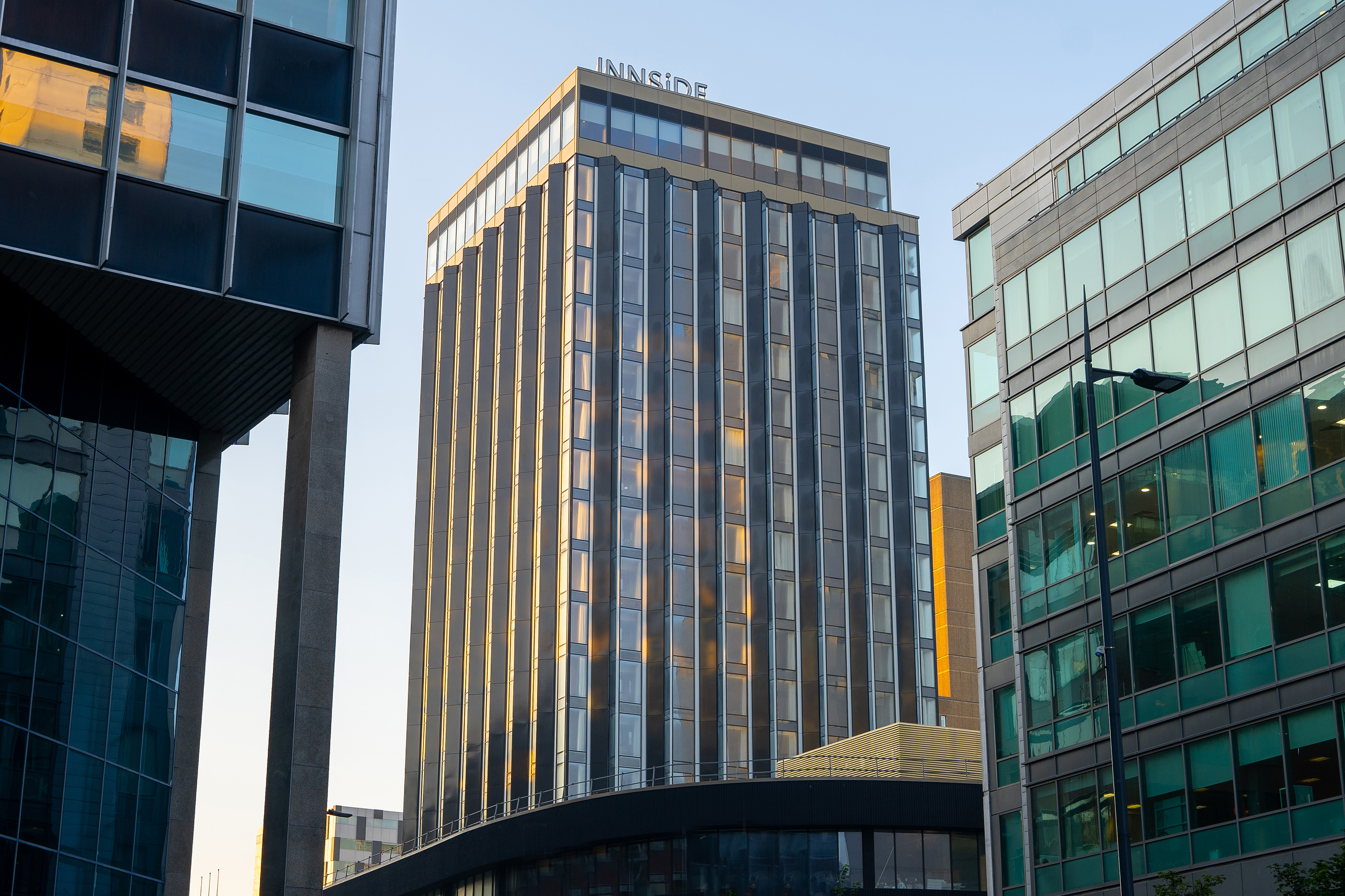 Innside skyscraper with reflective glass facade, bathed in golden sunlight, urban setting.
