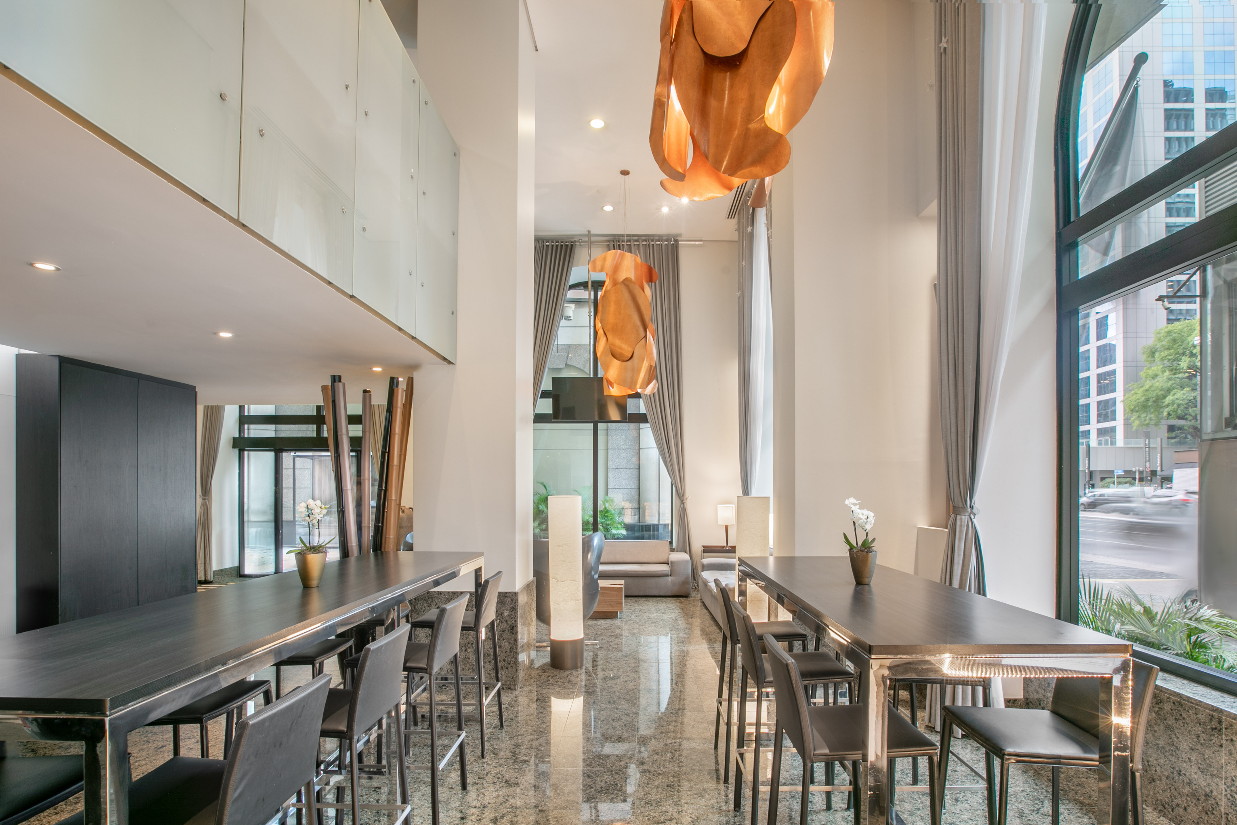 Contemporary lounge with communal bar tables, stools, and city views.