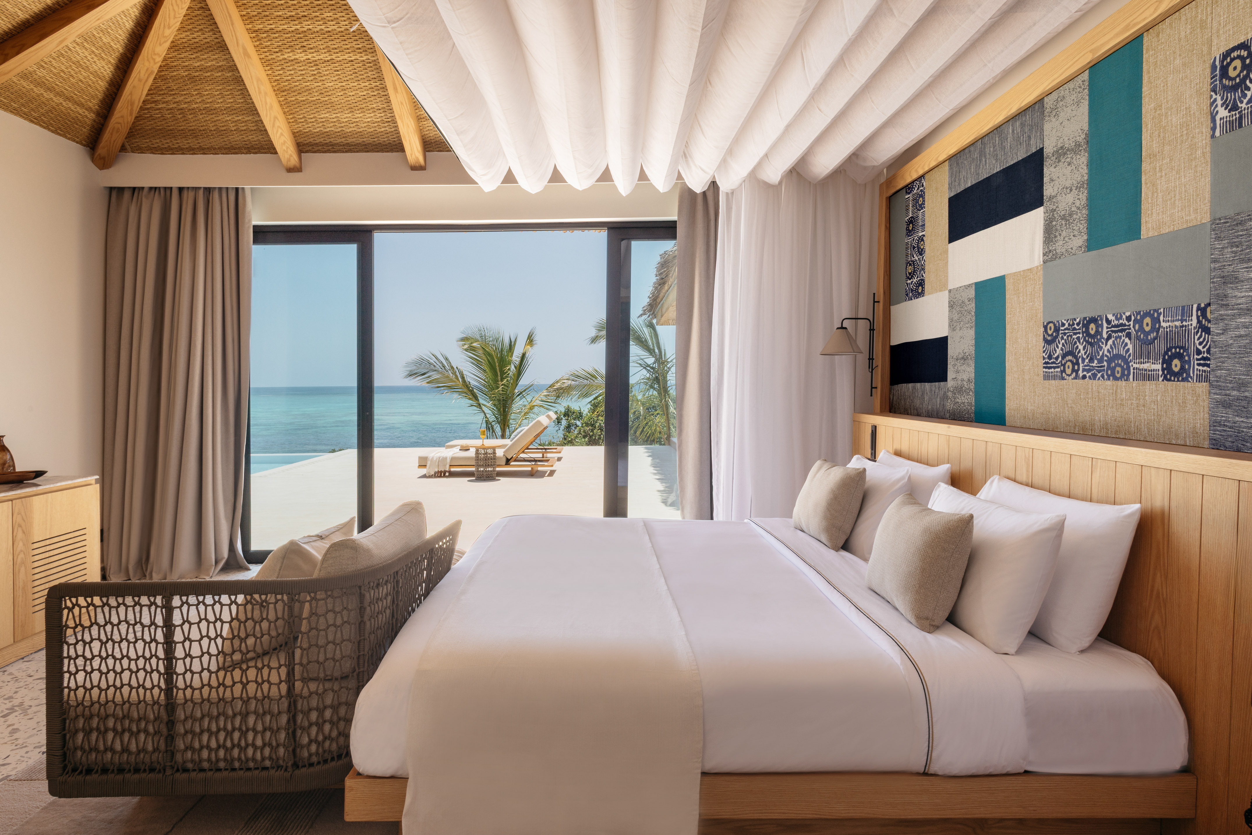 Luxury tropical bedroom with ocean view, king bed, and private lounge deck.