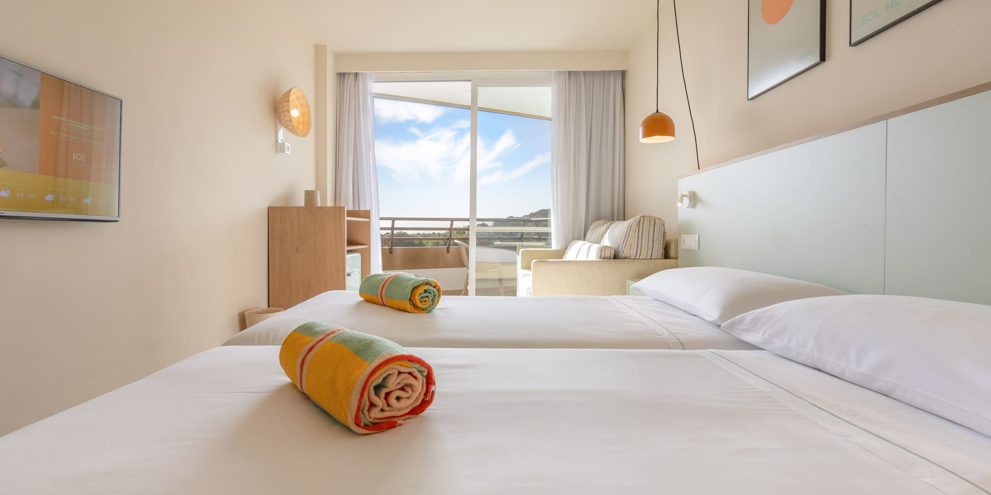 Sol Hotels room with twin beds, balcony view, and colorful towels.