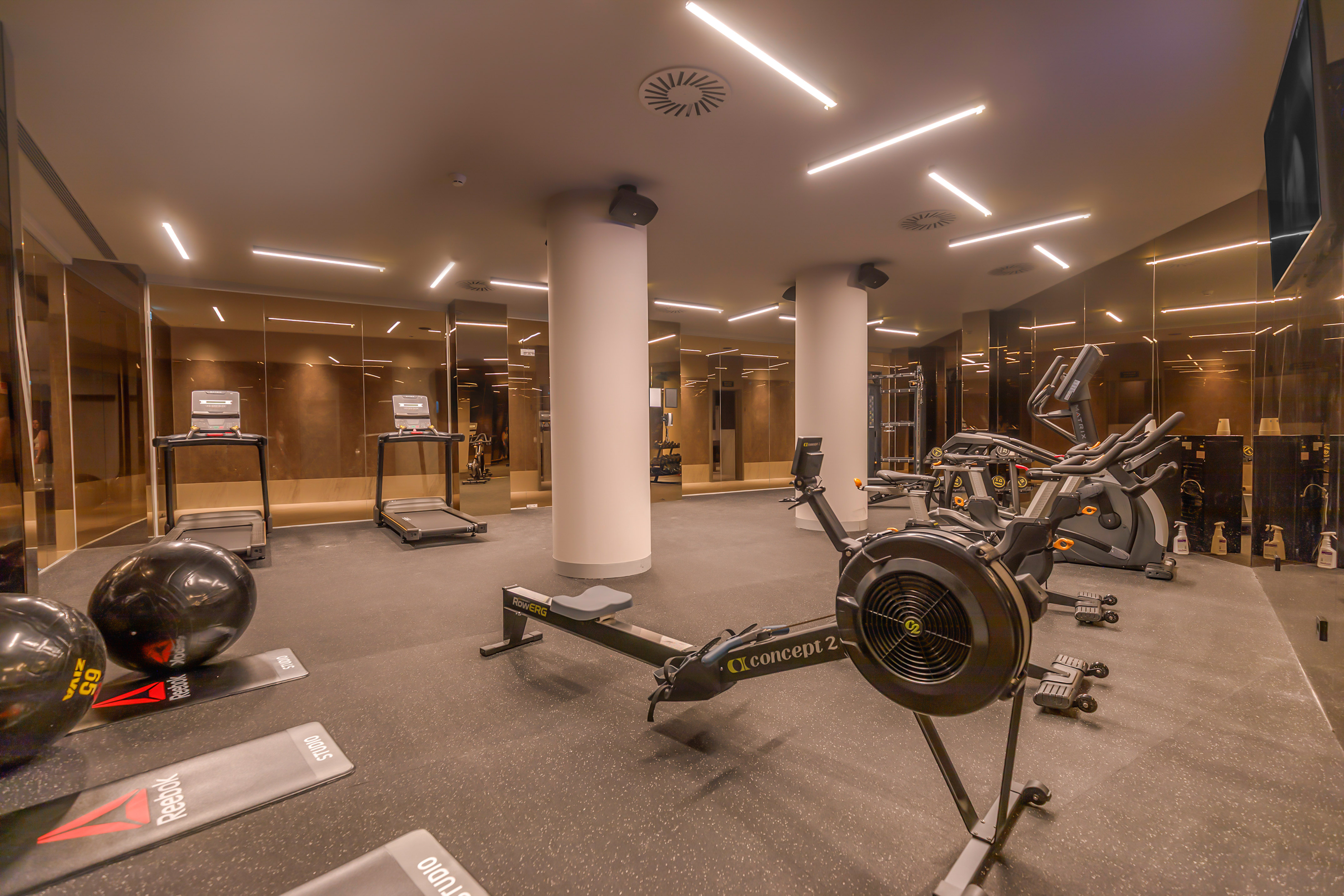 Modern gym with treadmills, rowing machine, and exercise bikes.