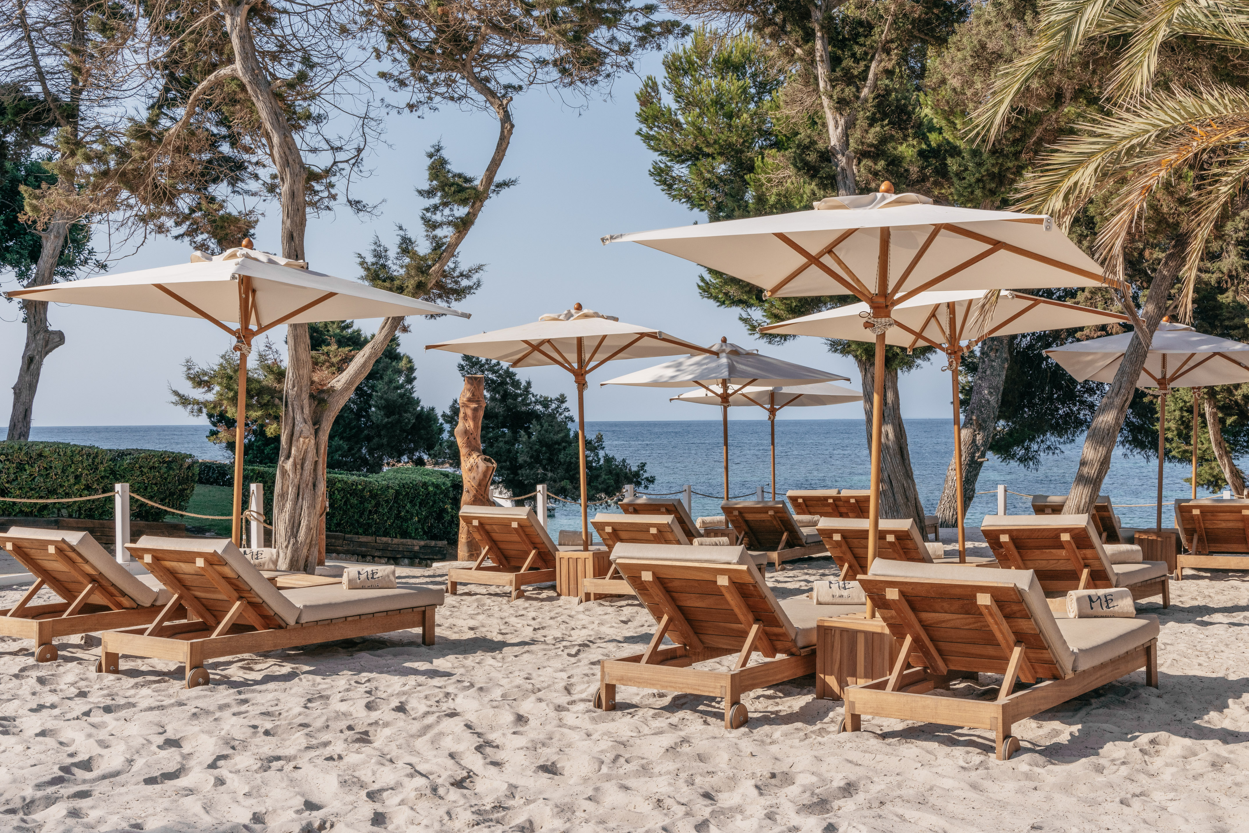 Beach resort with sandy shore, lounge chairs, umbrellas, and ocean.