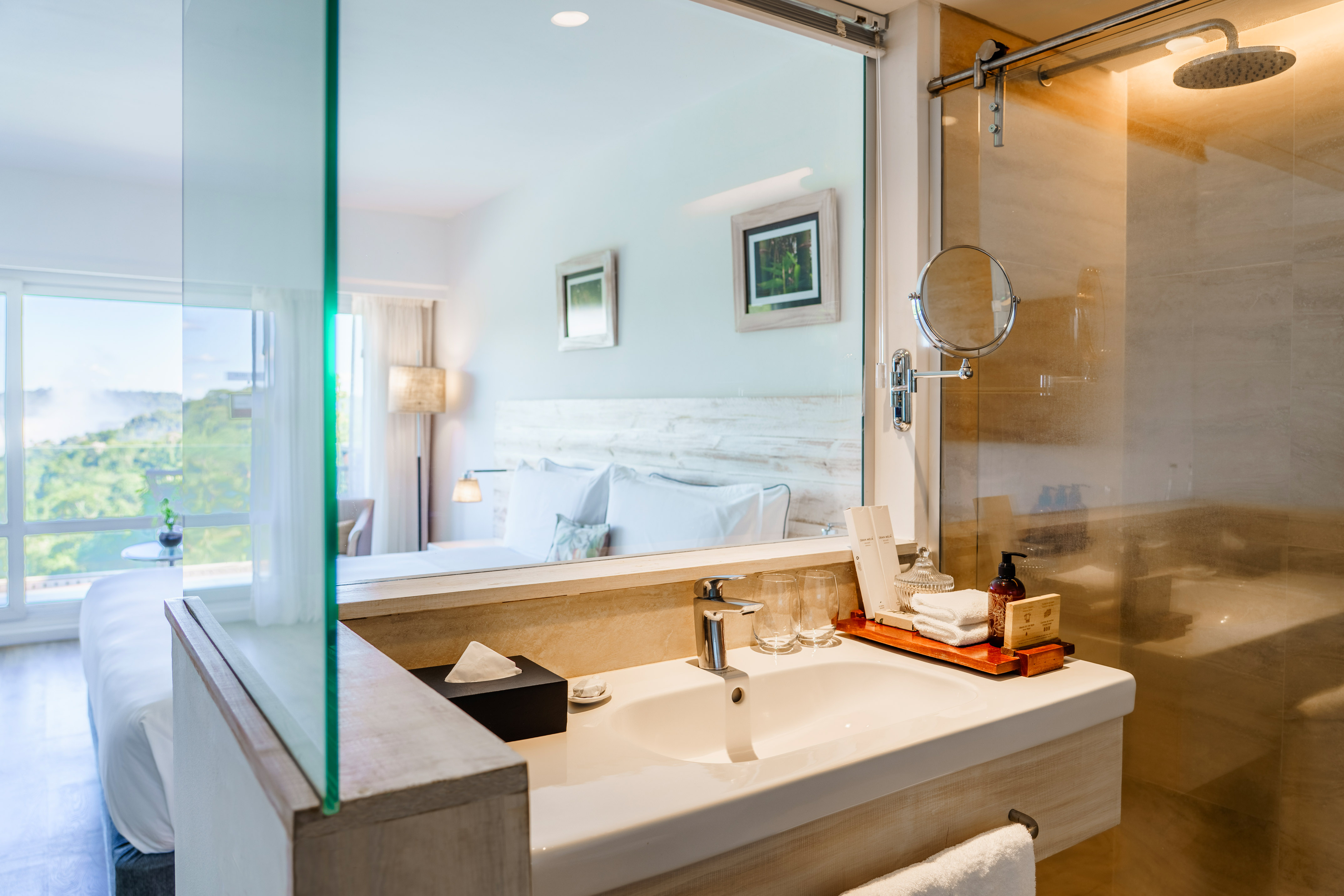 Modern hotel room with integrated bathroom, bedroom, and scenic view.