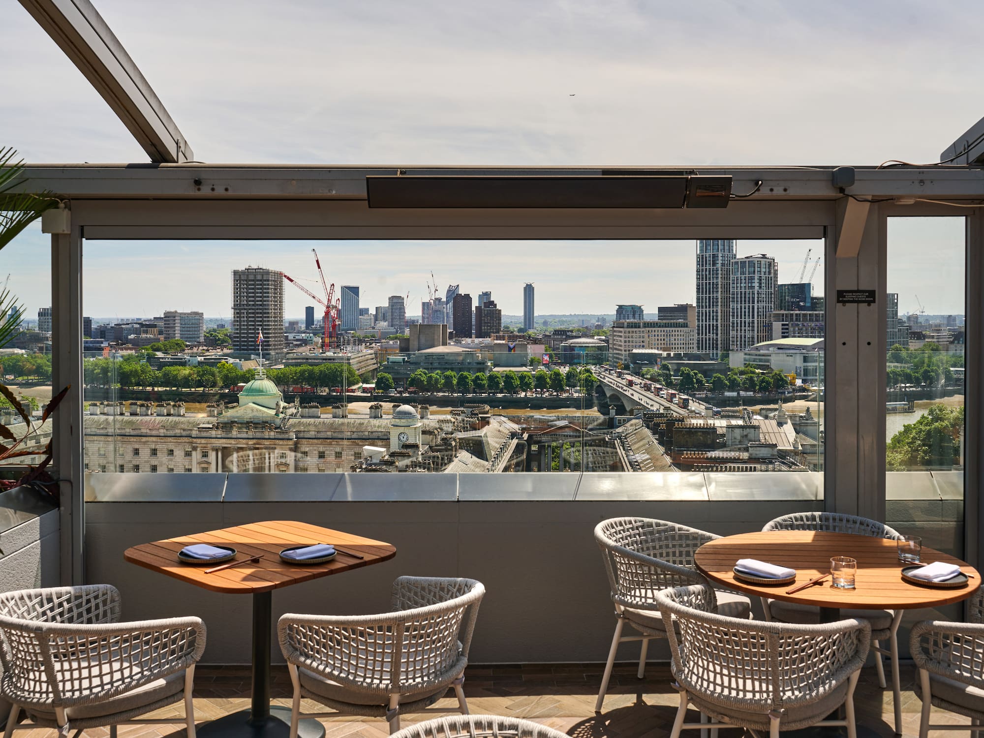A table and chairs set on a rooftop with a view of the city.