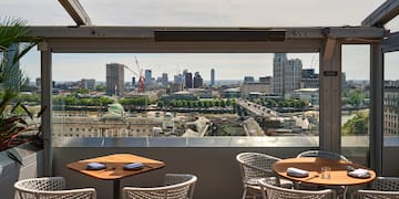 a table and chairs on a rooftop overlooking a city