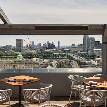 a table and chairs on a rooftop overlooking a city