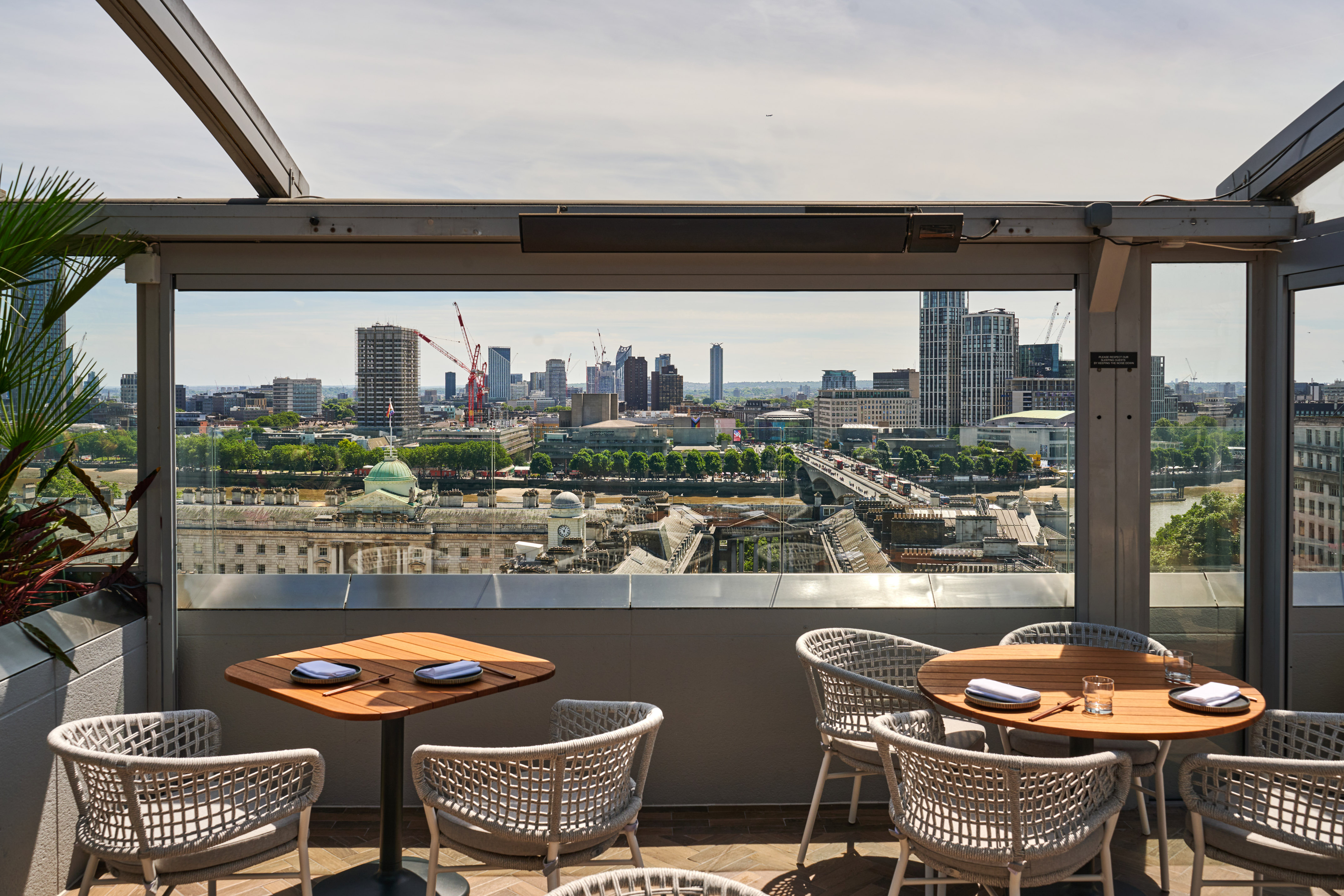 A table and chairs set on a rooftop with a view of the city.