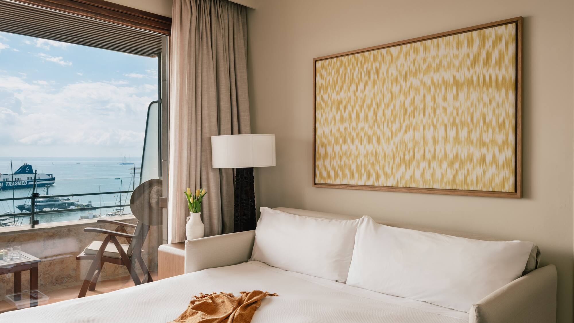 a bed with a blanket and a painting on the wall