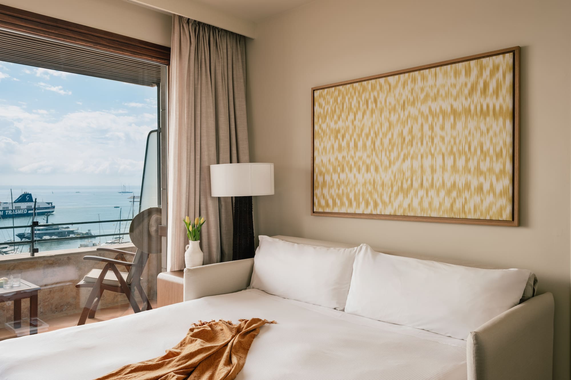 a bed with a blanket and a painting on the wall