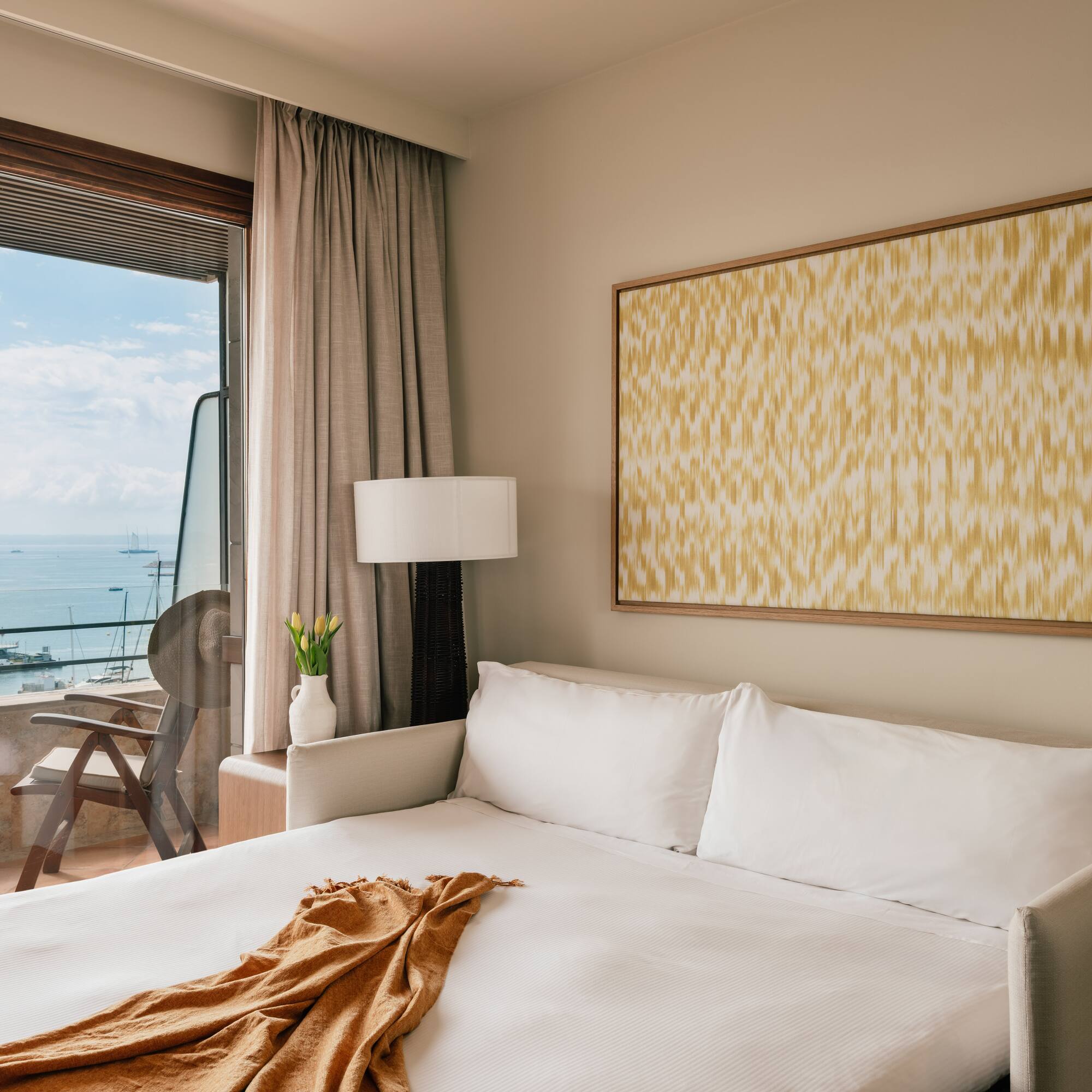 a bed with a blanket and a painting on the wall