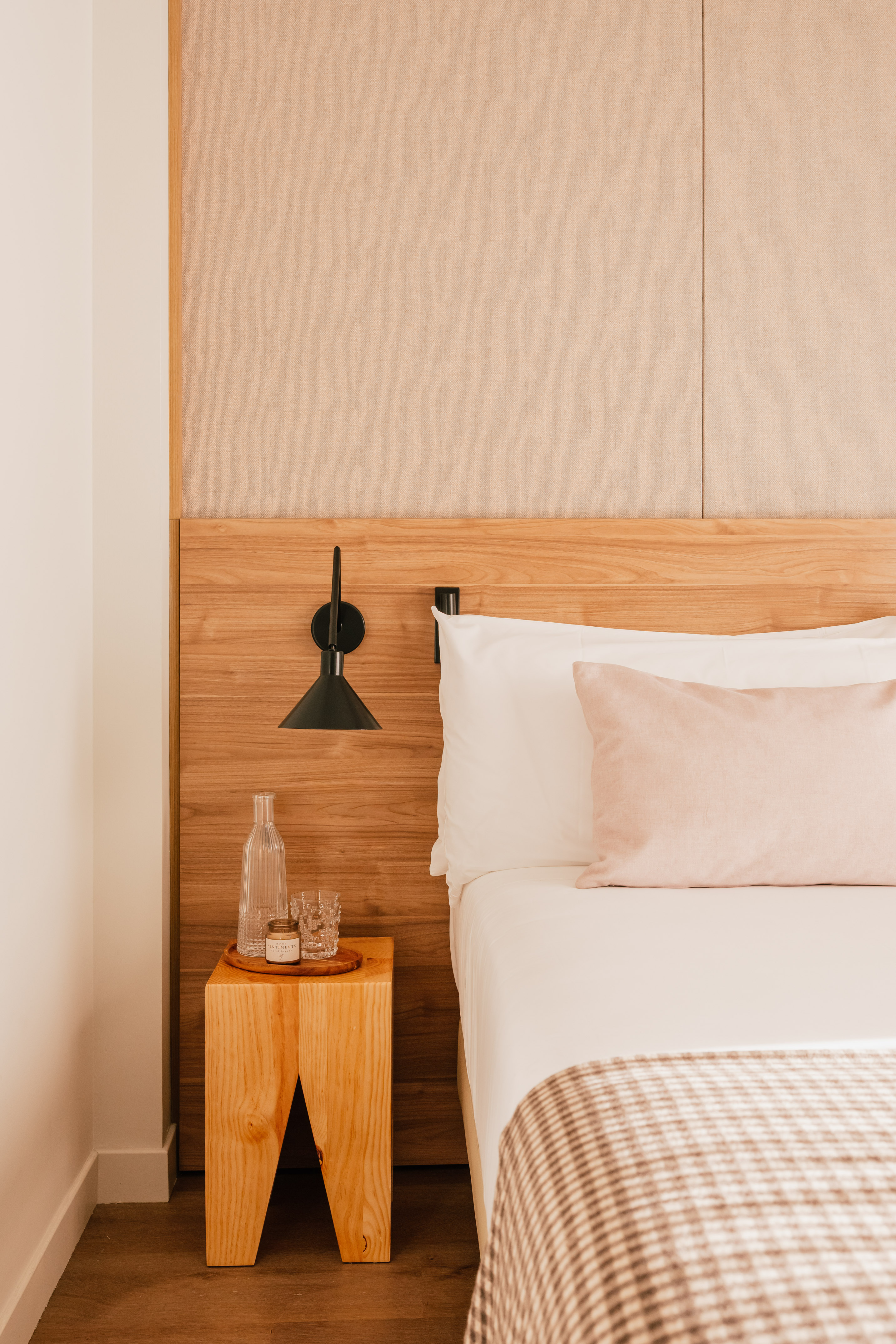 Modern bedroom: wood headboard, white bed, pink pillow, and bedside table.