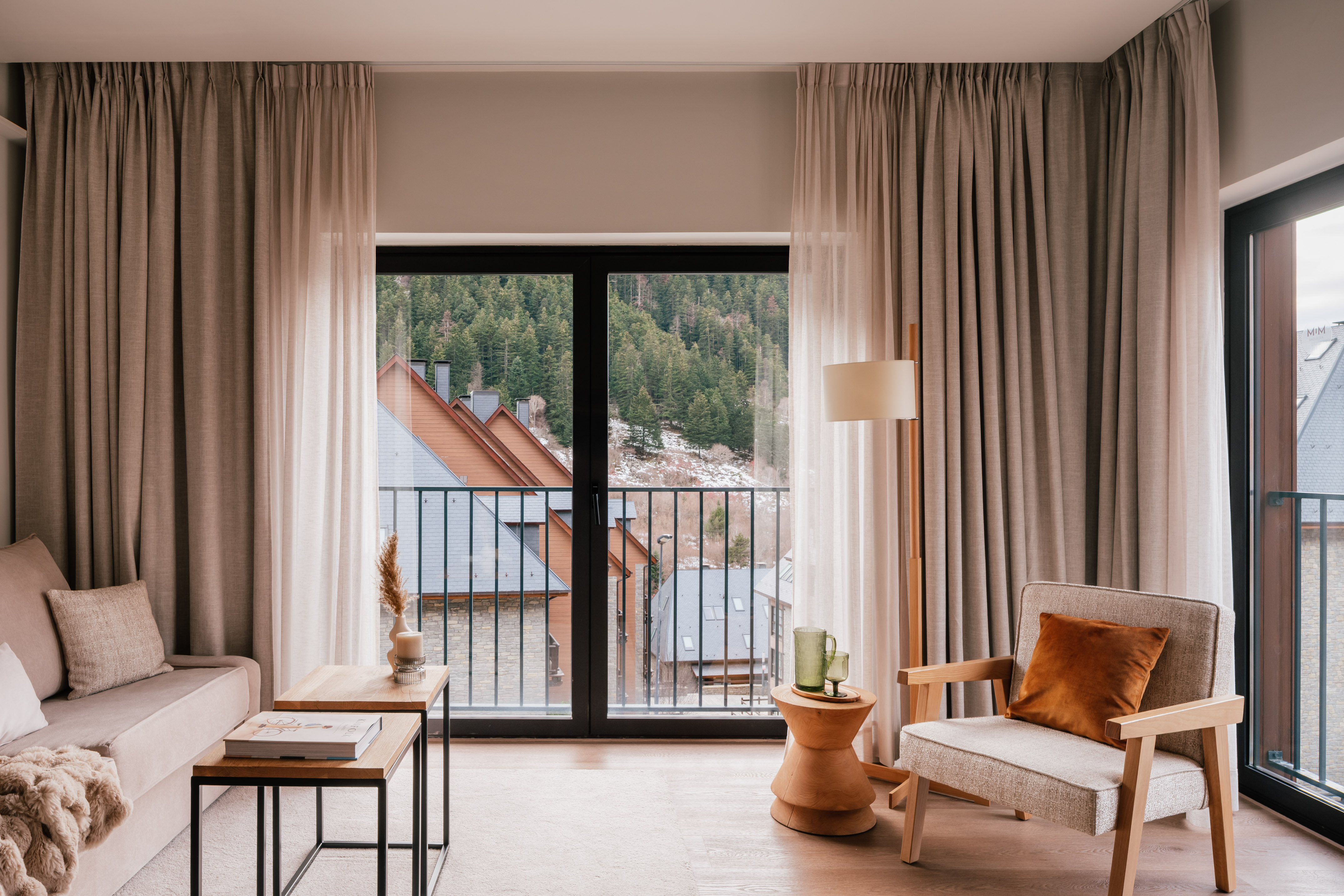 Modern apartment living room with balcony view of mountain forest village.